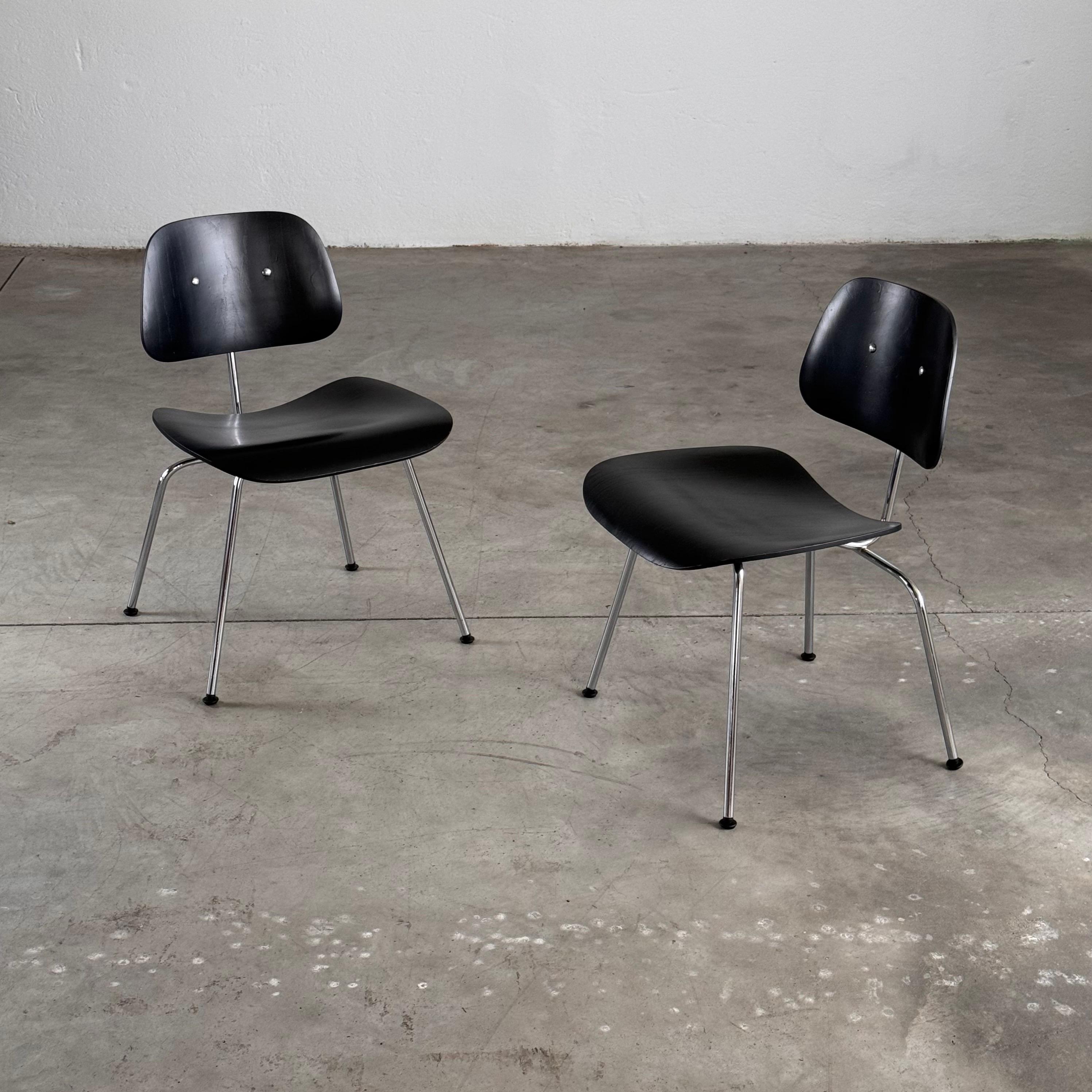 This pair of original black aniline-dyed DCM (Dining Chair Metal) chairs by Charles and Ray Eames, produced by Herman Miller, is an outstanding example of mid-century modern design. First introduced in 1946, the DCM chair reflects the Eameses'