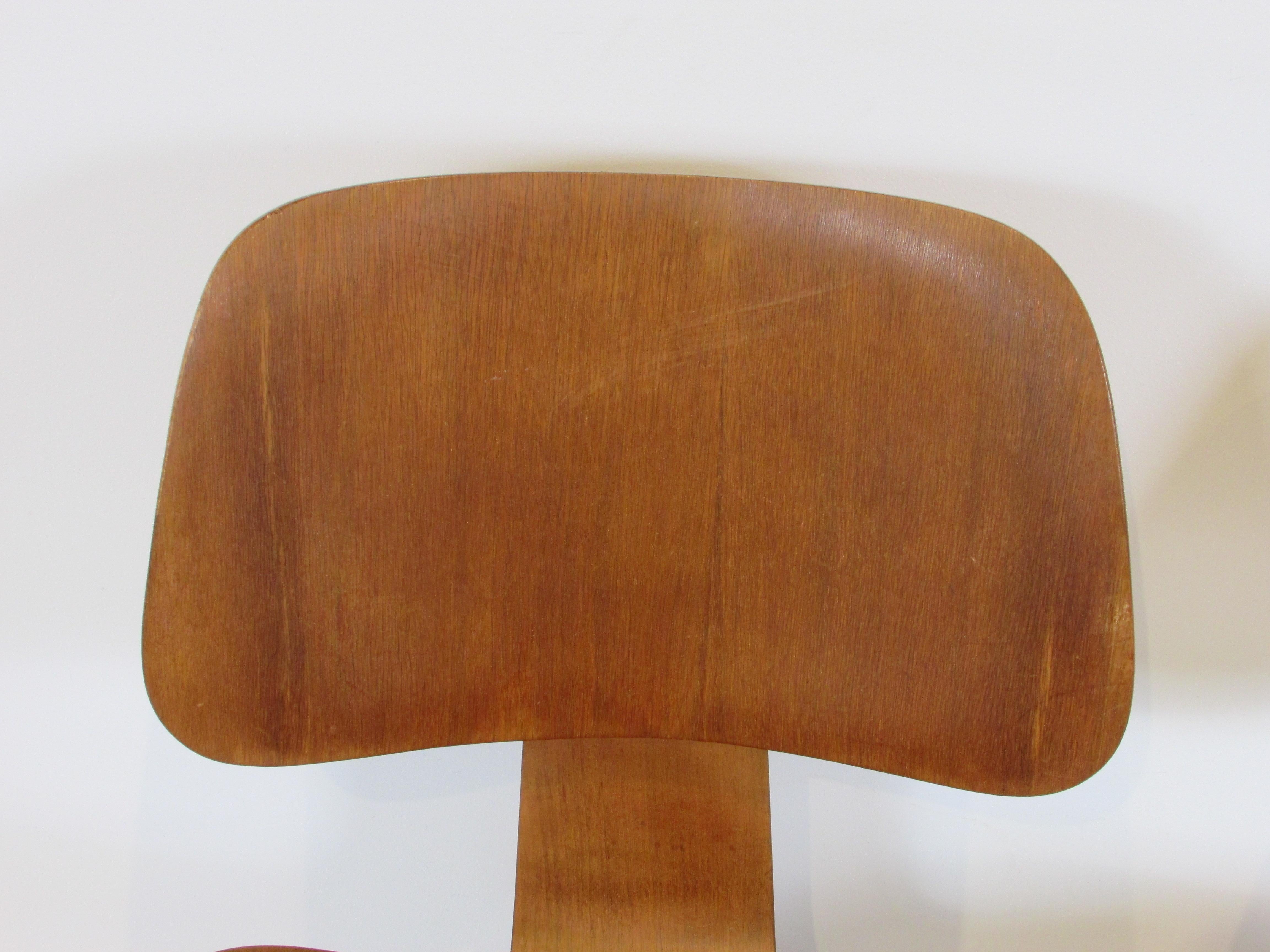 Laminate Pair of early Eames Evans Herman Miller walnut DCW chairs with labels For Sale
