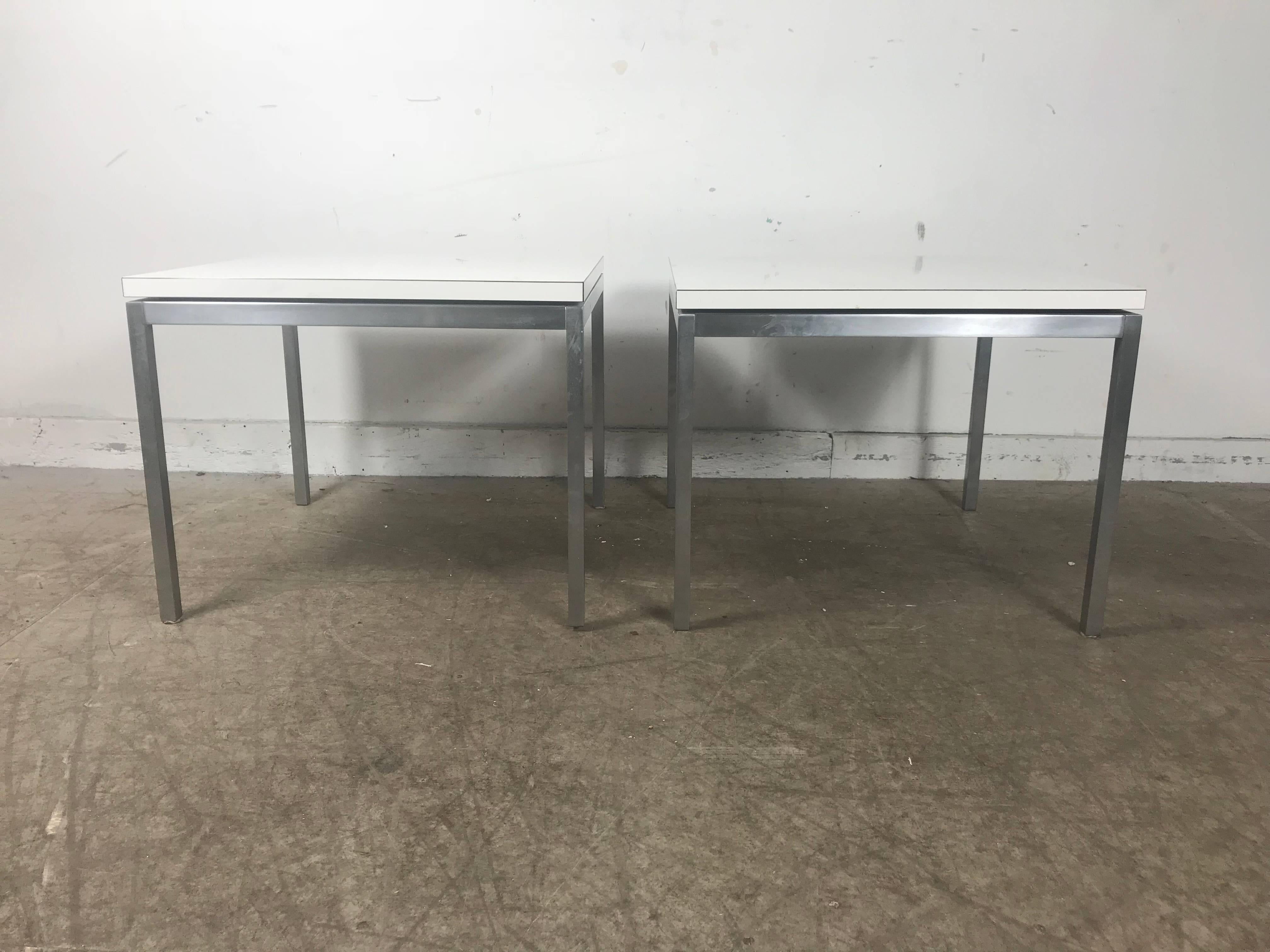 Pair of early Florence Knoll for Knoll stainless steel and laminate side tables, original white laminate tops, stainless steel bases, retains early Knoll label, sleek simple, Classic modernist design.