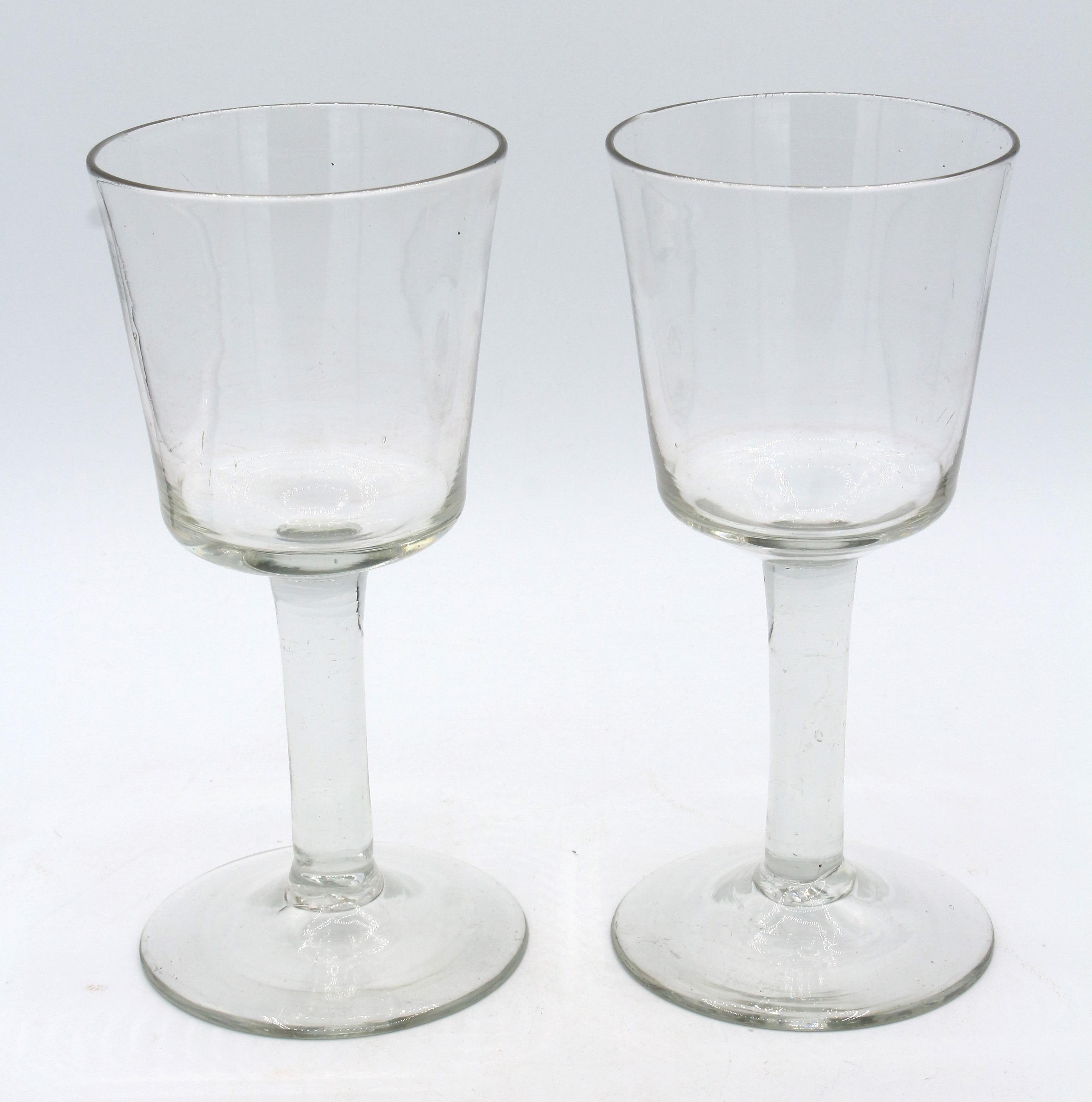 Paar frühe georgianische Gläser, um 1740, England. Handgefertigt, jeweils mit Eimerschale auf einfachem Stiel. Großzügige konische Füße. Intakte Paare sind selten zu finden. Gute Farbe, Rillen und Werkzeugspuren. Grob geknickte Brückenpfeiler.