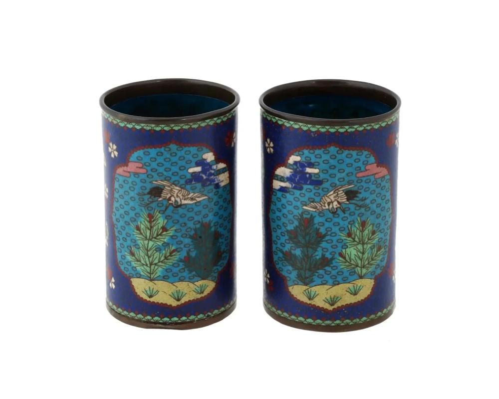 A pair of antique Japanese brush pots, Meiji era, 1868 to 1912. The exterior of both matched pieces is enameled with polychrome enamel blossoming flowers and butterflies on a cobalt blue ground. Two turquoise colored medallions are decorated with an
