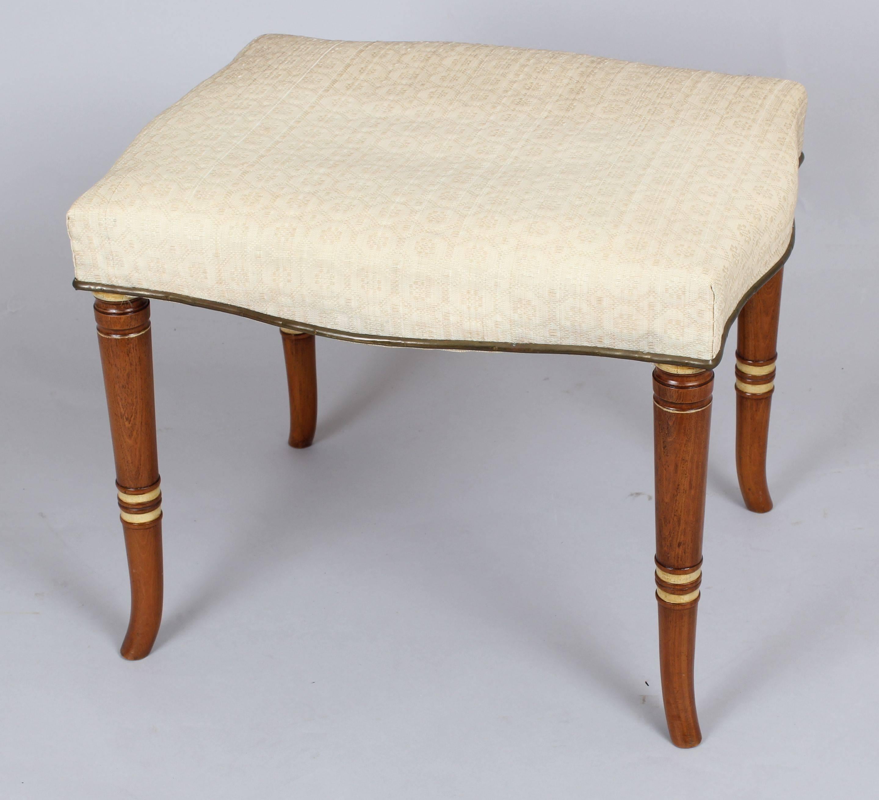 Pair of early 19th century Continental stools; the serpentine stuff-over seats covered (about twenty years ago) in cream woven horsehair with brass trim; on pale beech turned and tapering legs. The seat-rails retain their original cross-struts and