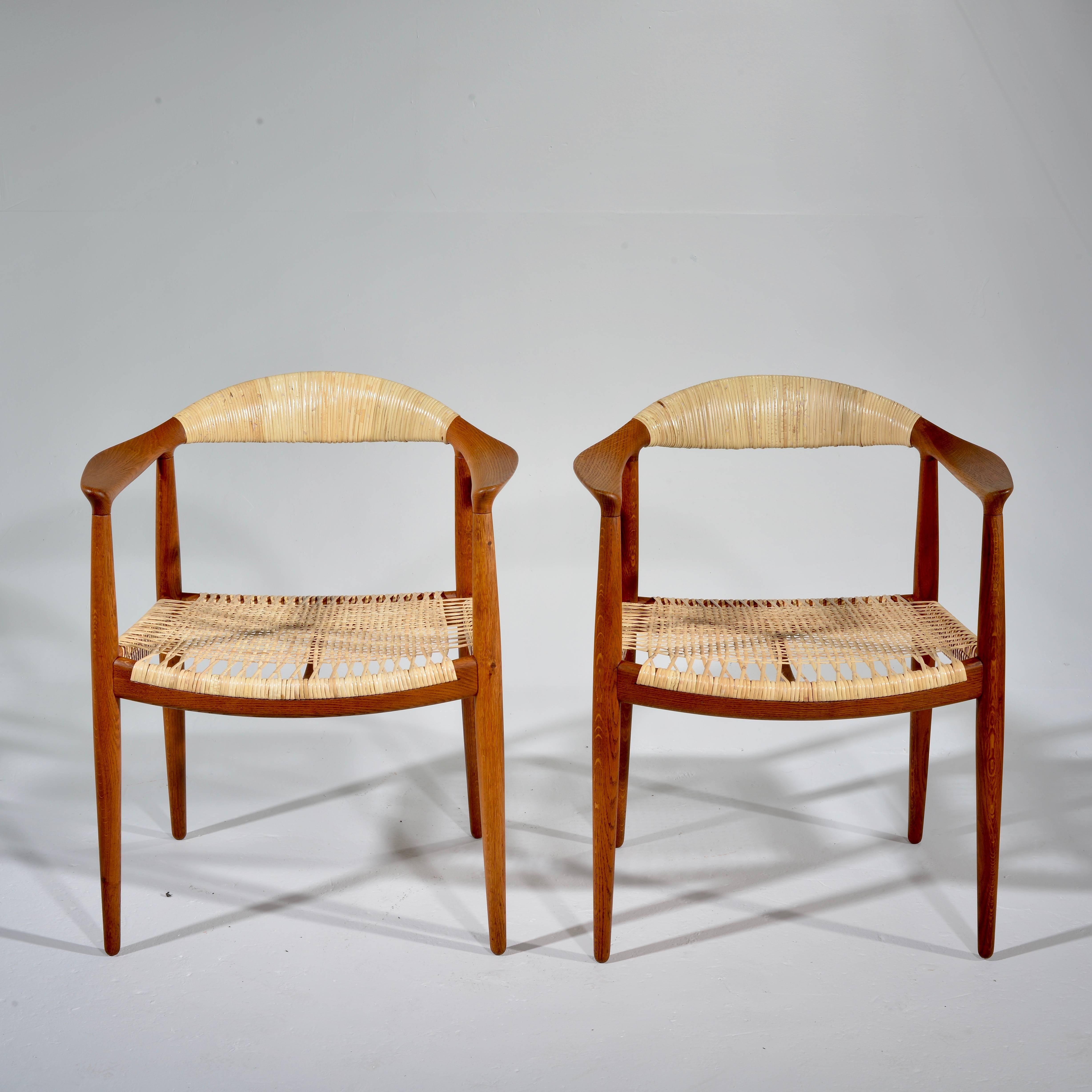 This is a pair of early oak and caned armchair by Hans Wegner for Johannes Hansen, Denmark. Excellent condition including new professionally crafted cane seats and backs.