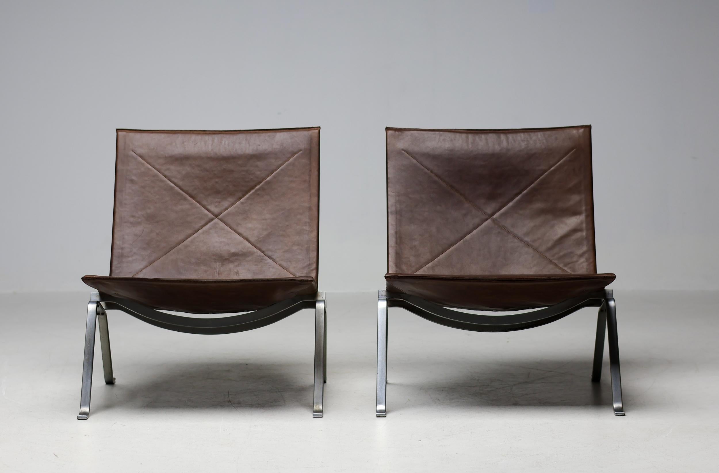 Rare paire de fauteuils PK 22 de Poul Steele en cuir brun foncé naturel avec structure en acier chromé mat. 
E. Kold Christensen dans le cadre sous le siège.


