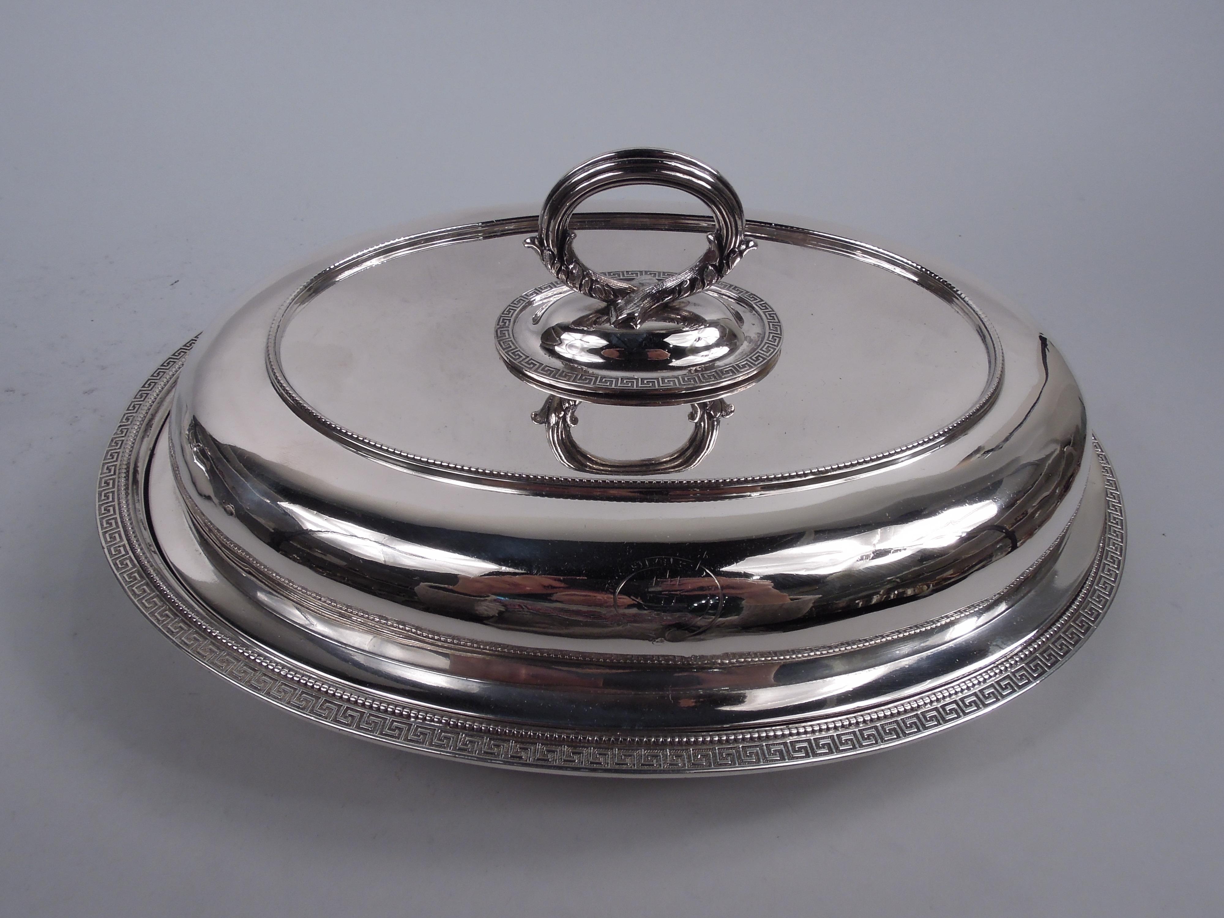 Pair of early Etruscan sterling silver covered serving dishes. Made by Moore for Tiffany & Co. at 550 Broadway in New York. Each: Oval bowl with everted rim. Cover domed; top has cast leaf-wrapped and reeded twist-lock ring handle for converting to