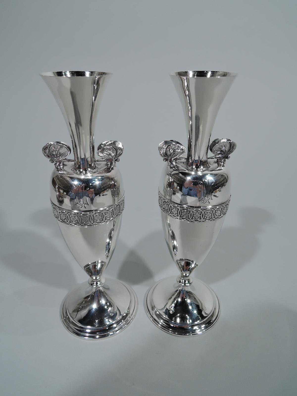 Pair of early sterling silver Greek Revival vases. Retailed by Tiffany & Co. in New York. Each: Amphora with ovoid body, spread and stepped domed foot, and trumpet neck and mouth. Tooled band with rosettes in interlaced circles on vertical lines.