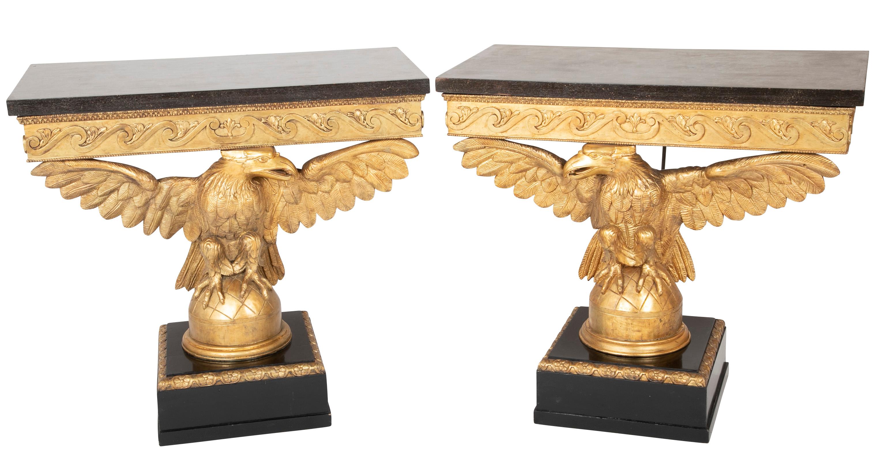 Pair of early to mid-19th century giltwood eagle console tables (opposing) with faux marble tops, vetruvian scroll aprons and plinth bases.