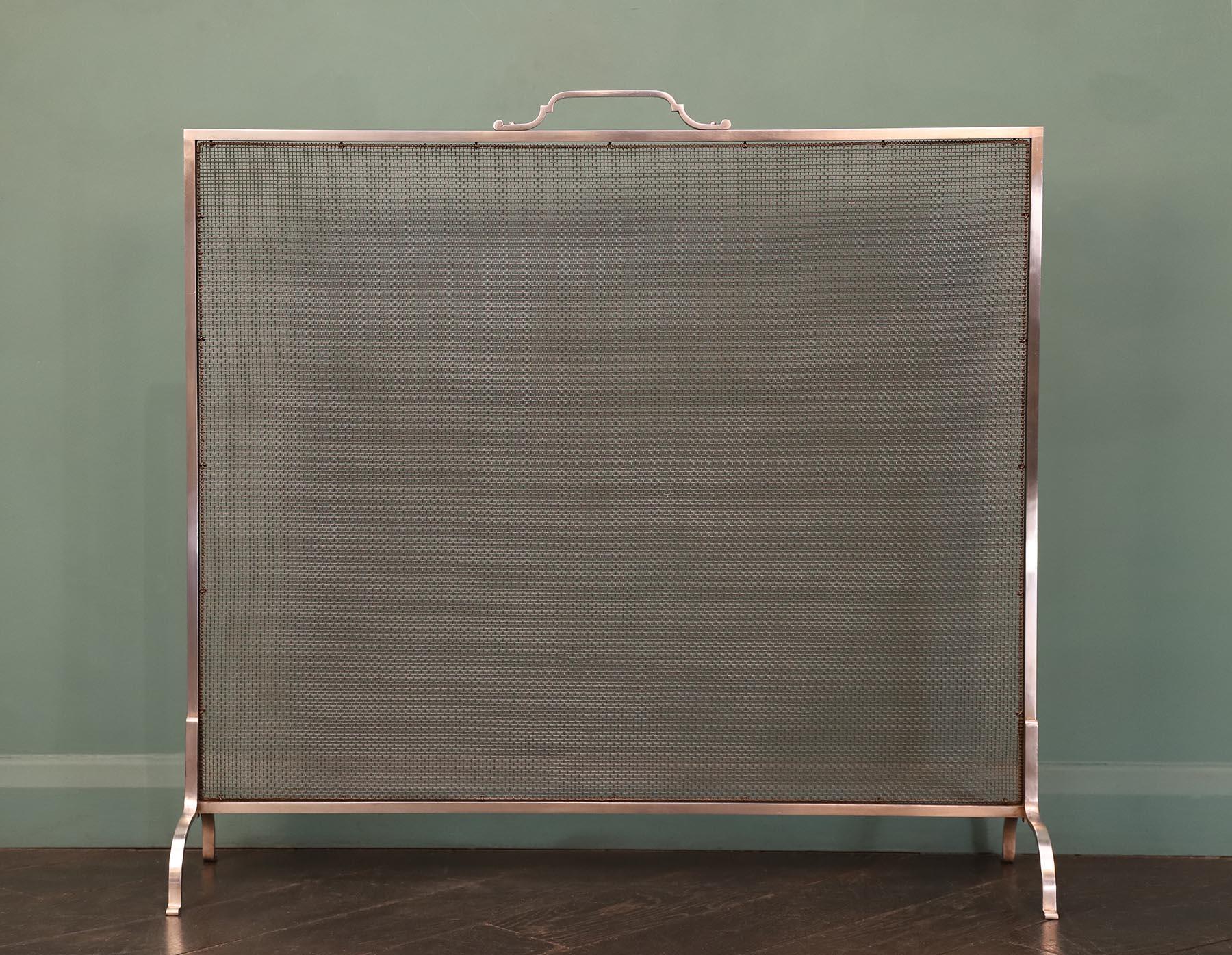 A pair of early twentieth century polished stainless steel fire screens with Art Deco details. Fine spark mesh panel held within stainless steel frame with shaped handle and supported on arched supports. ‘Stainless’ mark on underside. 