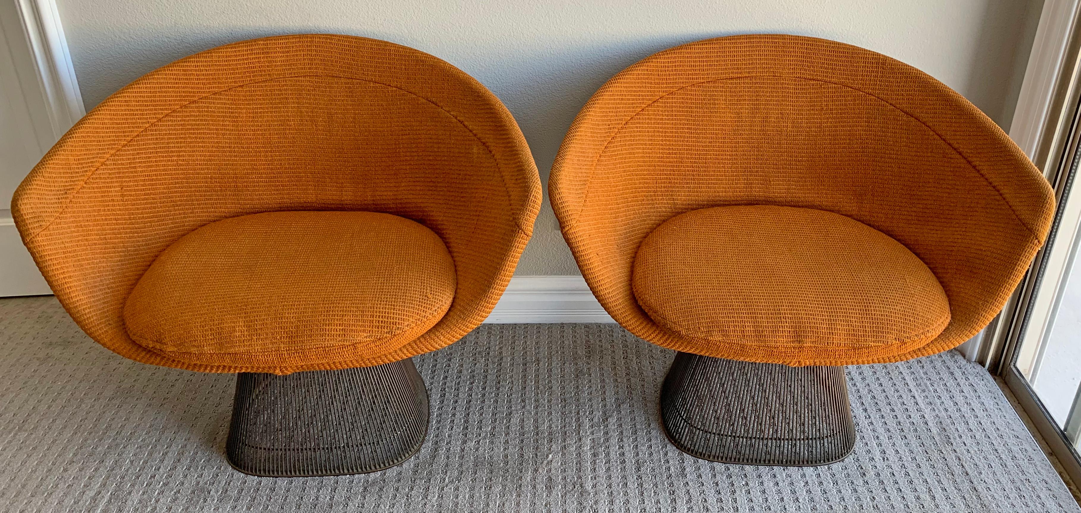 An absolutely wonderful pair of Warren Platner bronze lounge chairs. These early lounge chairs feature their original orange nubby upholstery, original tags (on both chairs) and original stickers that read 