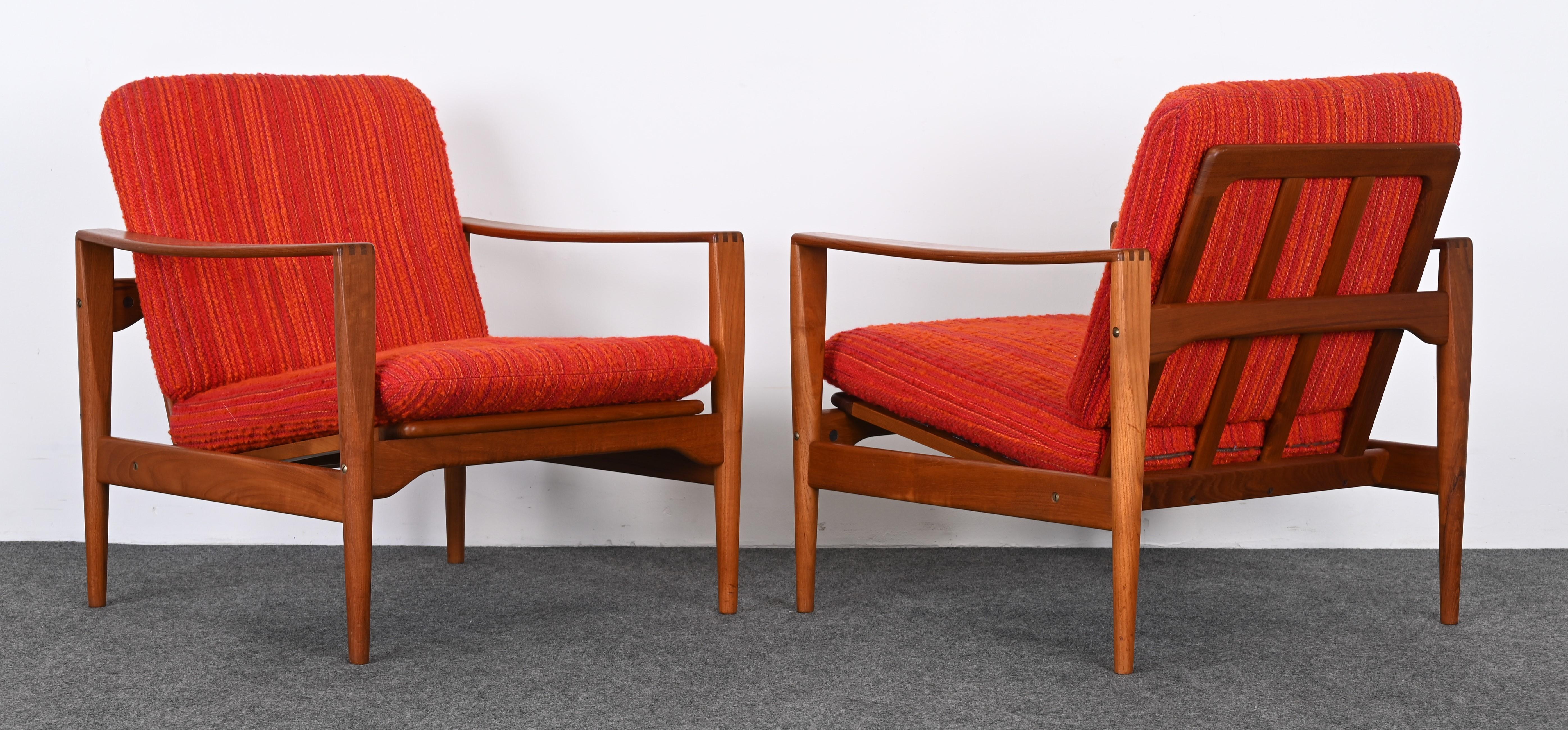 A Scandinavian Modern pair of Easy Chairs by Illum Wikkelso for Niels Eilersen. The pair of teak armchairs are covered with the original multi-colored fabric similar to boucle. The elegant pair of lounge chairs have new strapping, as shown in the