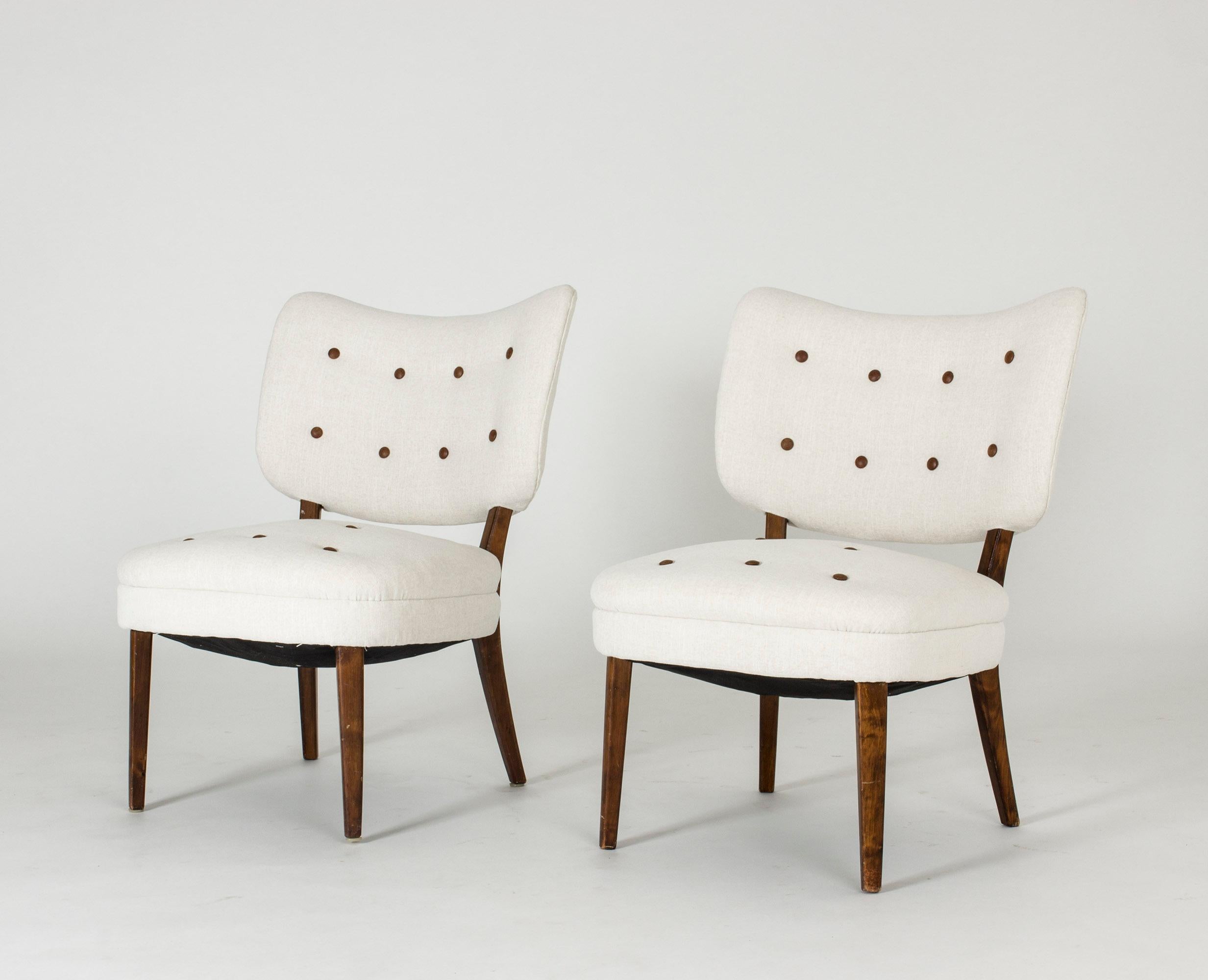 One elegant easy chair by Otto Schulz. White fabric with dark leather buttons, stained wooden legs.