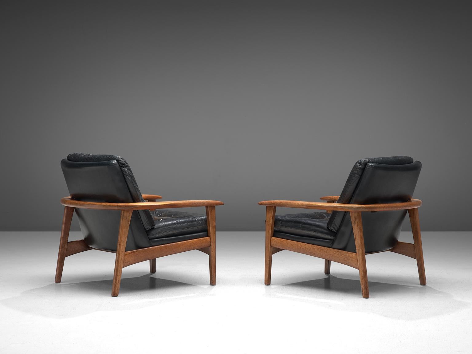 Pair of easy chairs, black leather and teak, Denmark, 1960s.

This set of easy chairs features a teak frame with a tufted seat and back. The chairs have a sturdy frame showing refined craftsmanship, holding a comfortable leather shell. The tufted