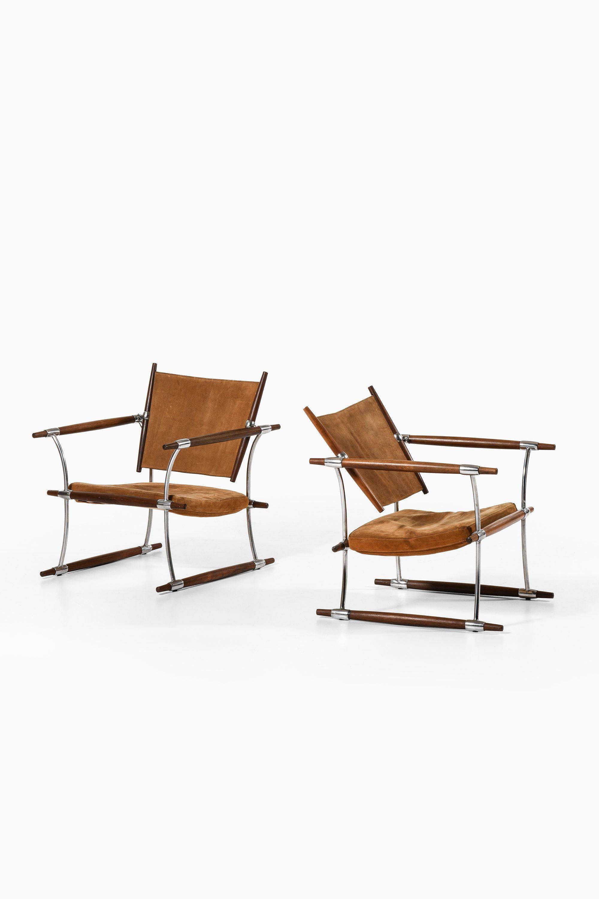 Pair of Easy Chairs in Rosewood and Chromium Plated Steel Frame, Seat Cushion and Back Upholstered with Brown Suede by Jens Harald Quistgaard, 1960's

Additional Information:
Material: Rosewood and chromium plated steel frame, seat cushion and back