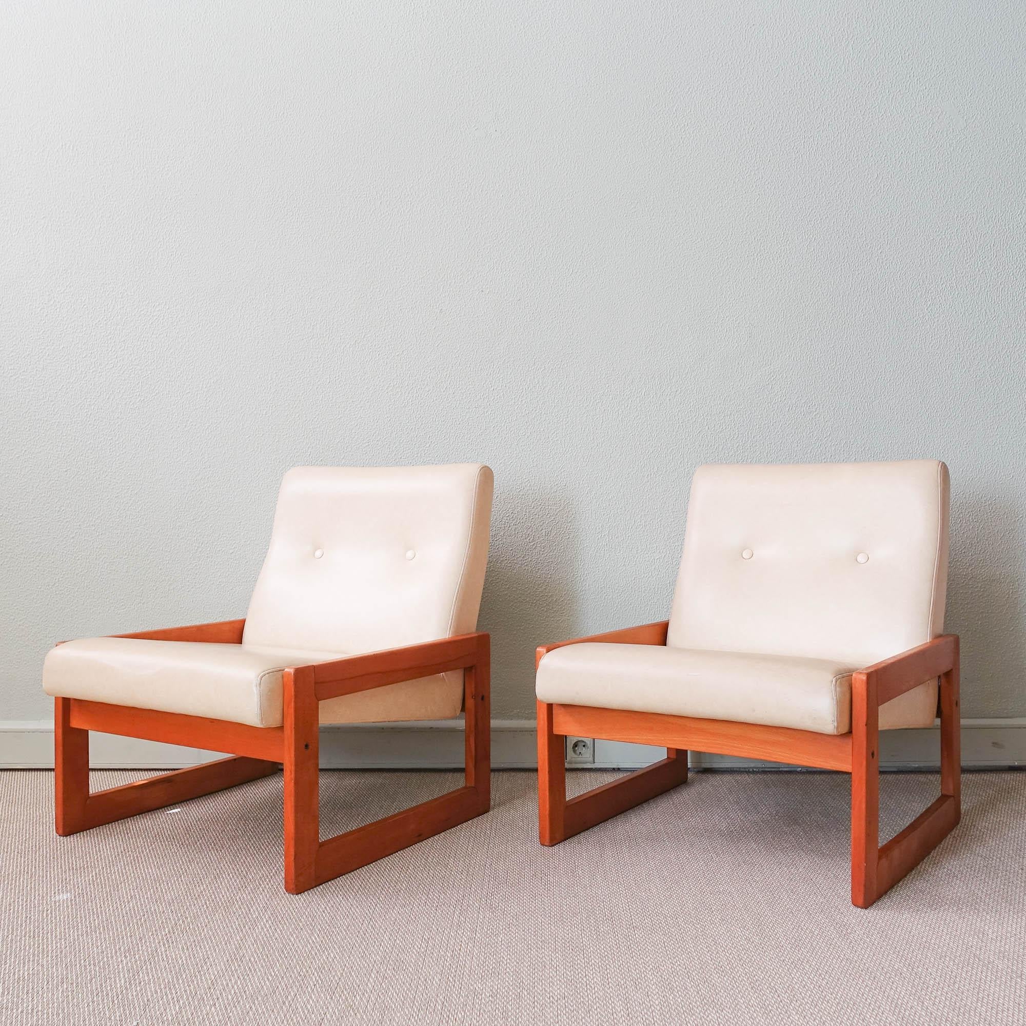 This pair of easy chairs, model Espinho, was designed by José Espinho for Olaio, in Portugal in 1973. The geometrical wood structure has clean and simple lines, where a upholstered white faux leather seat is set. They are in original and good