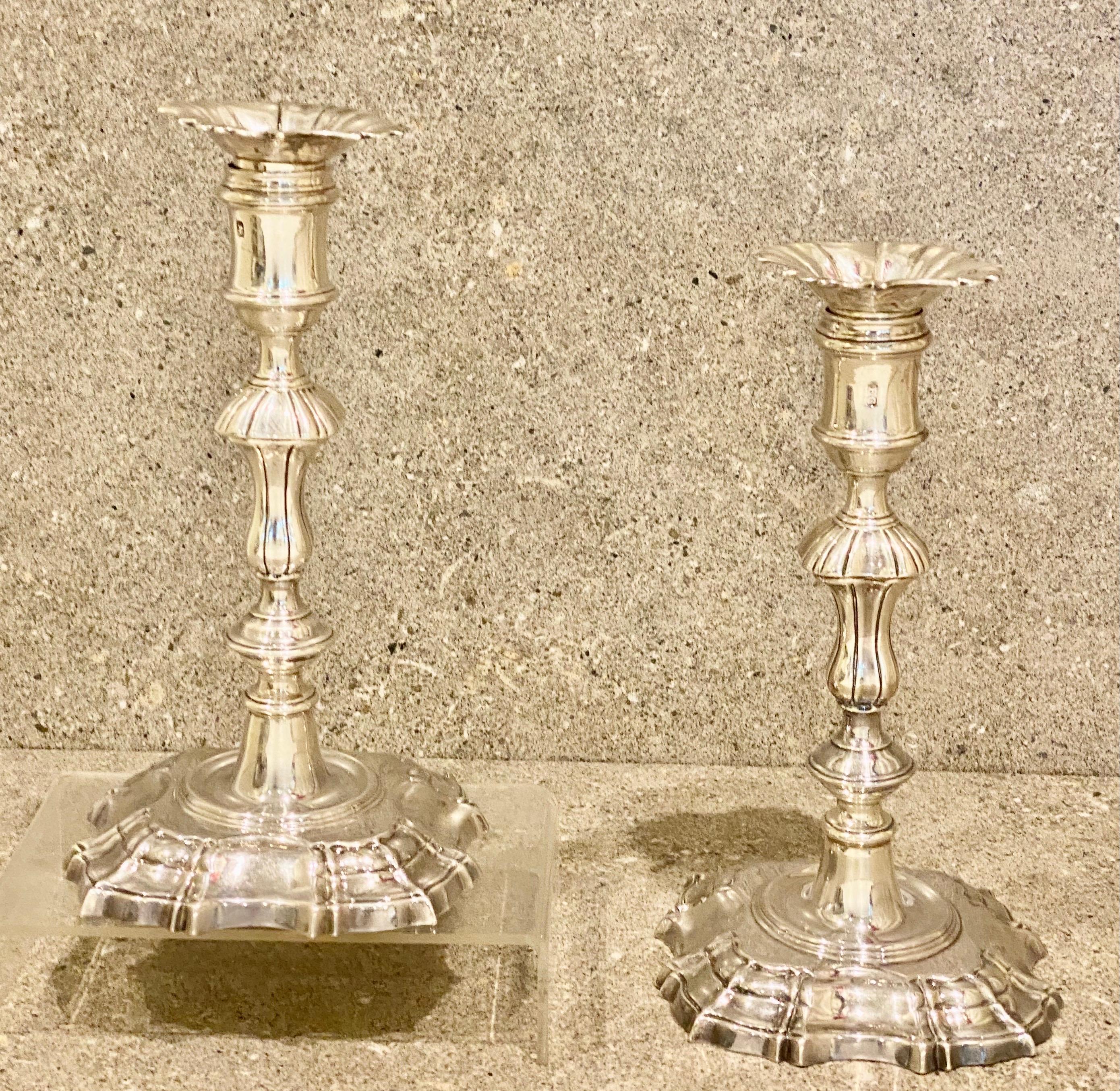 A fine pair by Ebenezer Coker, London 1768
Enhanced by knopped baluster stems with square shell corners, spool shaped capitals with detachable drip pans, the whole on shaped square bases with shell motifs, height 21cm, weight 1055gr 34oz.