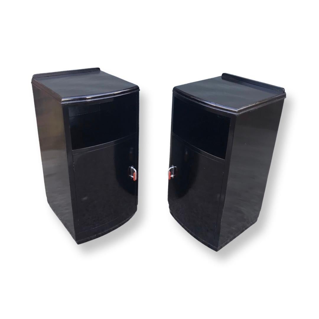 A striking pair of Art Deco ebonised nightstands/bedside cabinets in lovely condition. The bow fronted doors open to reveal a shelved interior. The doors have beautiful raspberry phenolic handles with bright chrome backplates which certainly make an