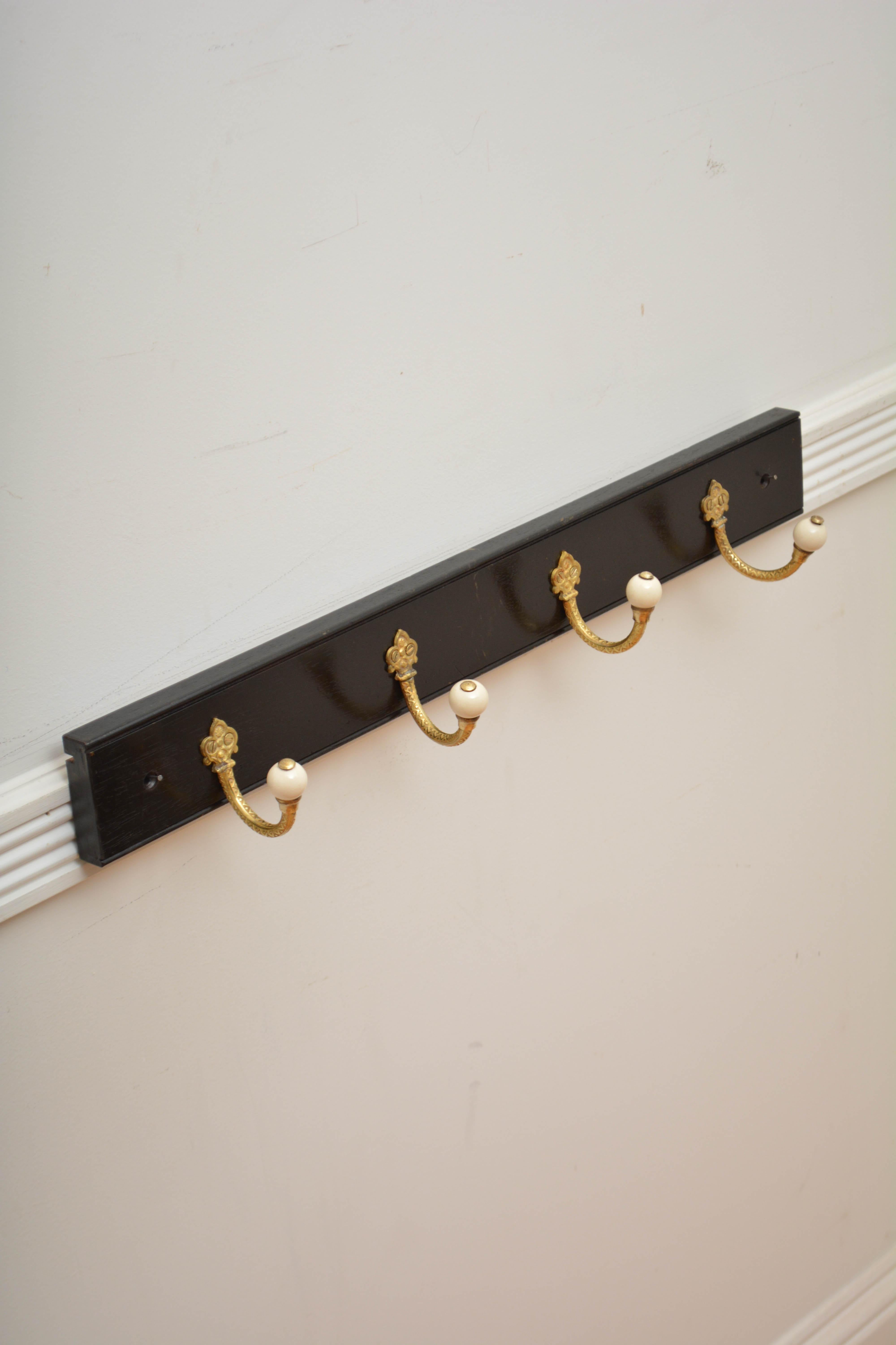 P0312 Two English coat racks, each having a very decorative set of four brass and ceramic Victorian coat hooks now on solid mahogany ebonised backing.  Cleaned, polished and ready to place at home. 

H3 1/4