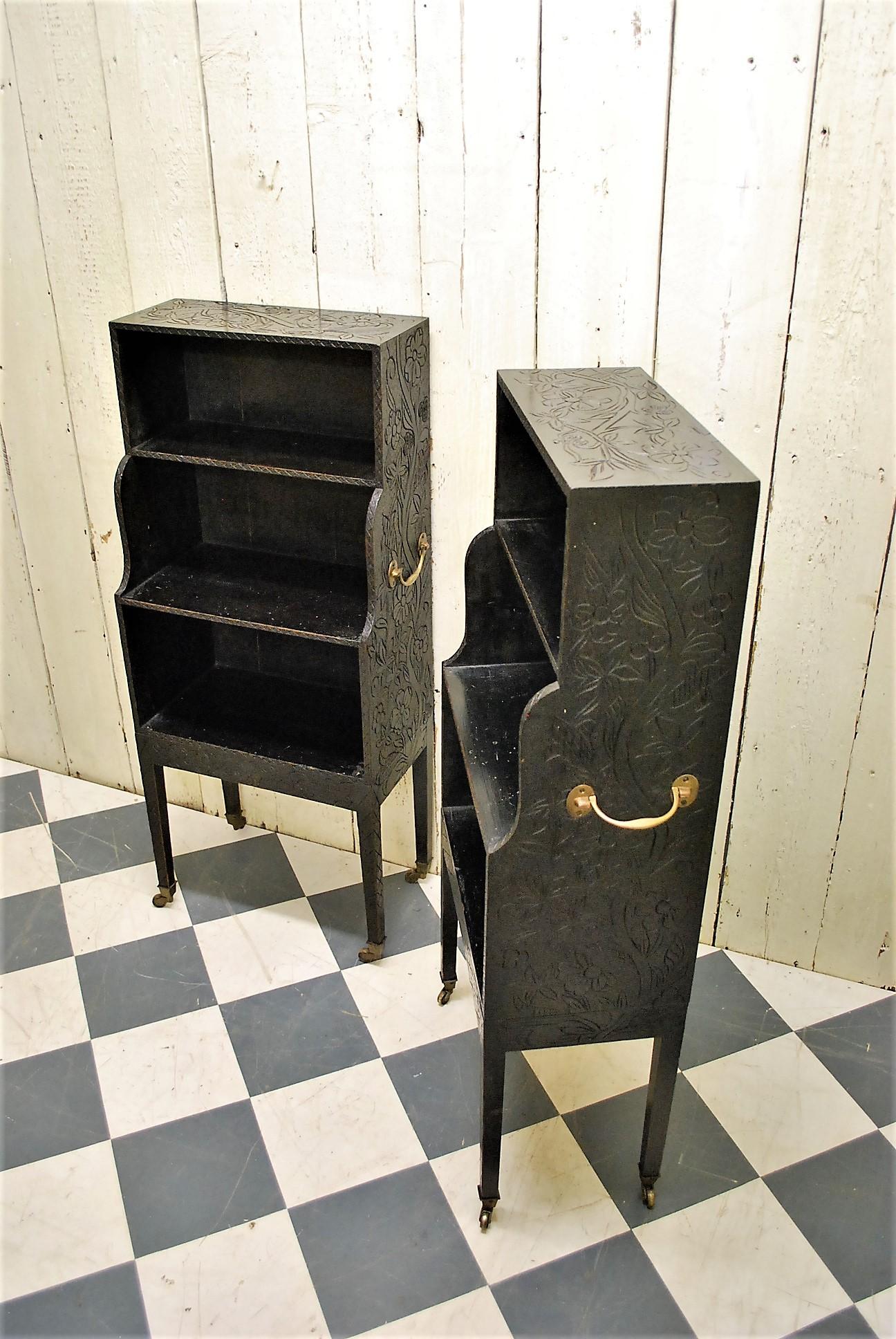 A rare pair of ebonized pine waterfall bookcases, in the Regency manner. Standing on tapered legs terminating in brass castors. Decorated with carved and stamped foliage. Matching brass carrying handles on both pieces. Hard to find one and even more