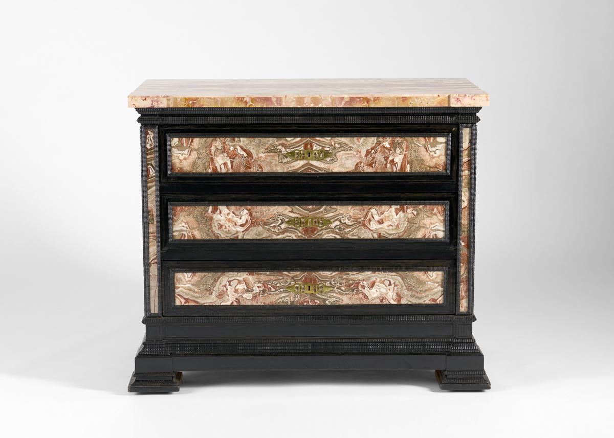 This commanding pair of three-drawer chests features exuberantly marbled veneer surfaces that contrast with the tooled, blackened wood of its construction. The colors of the marble range from whites to pinks, reds, and gold, each top piece boasting