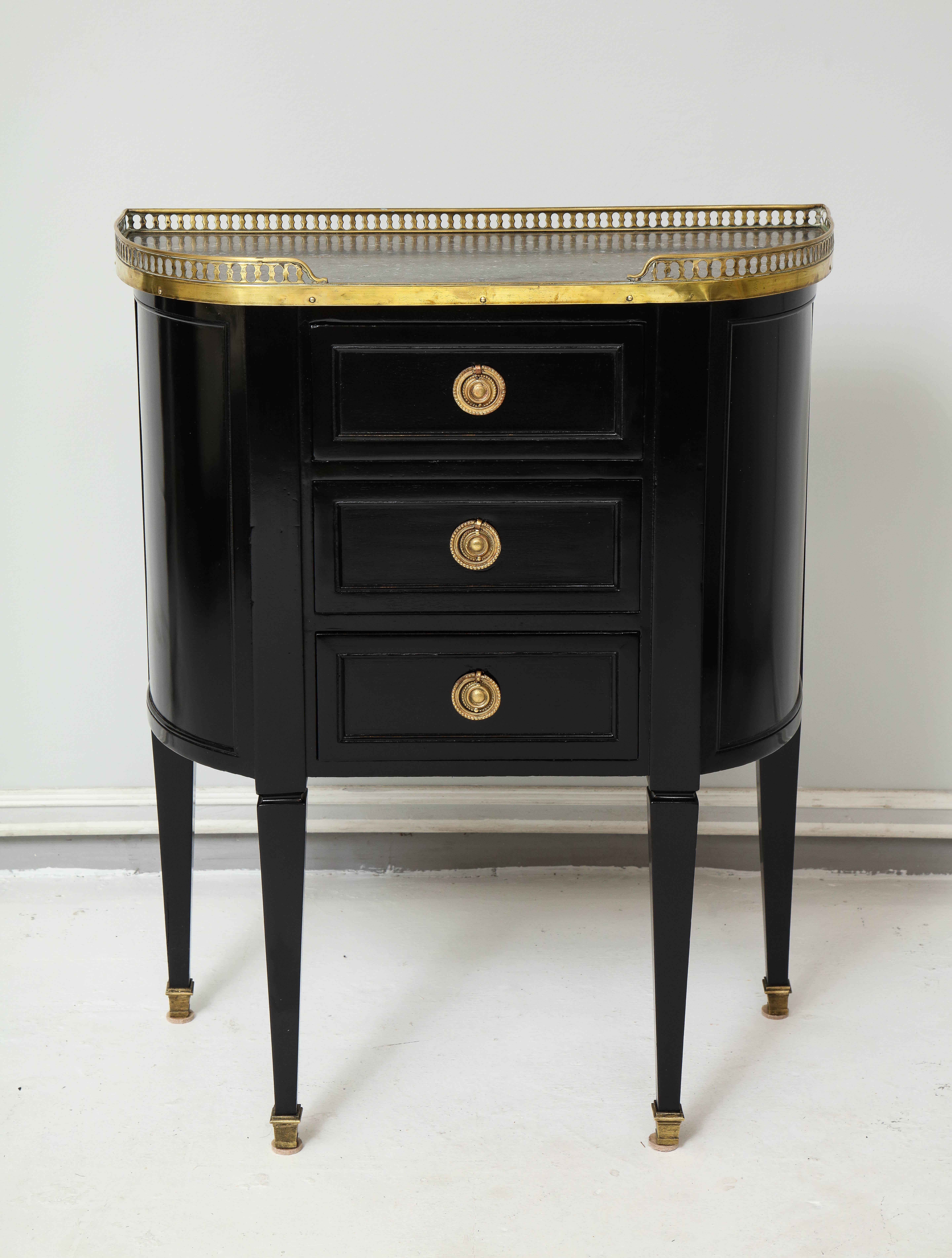 Pair of ebonized French marble-top petite commodes with brass gallery and pull-out drawers.