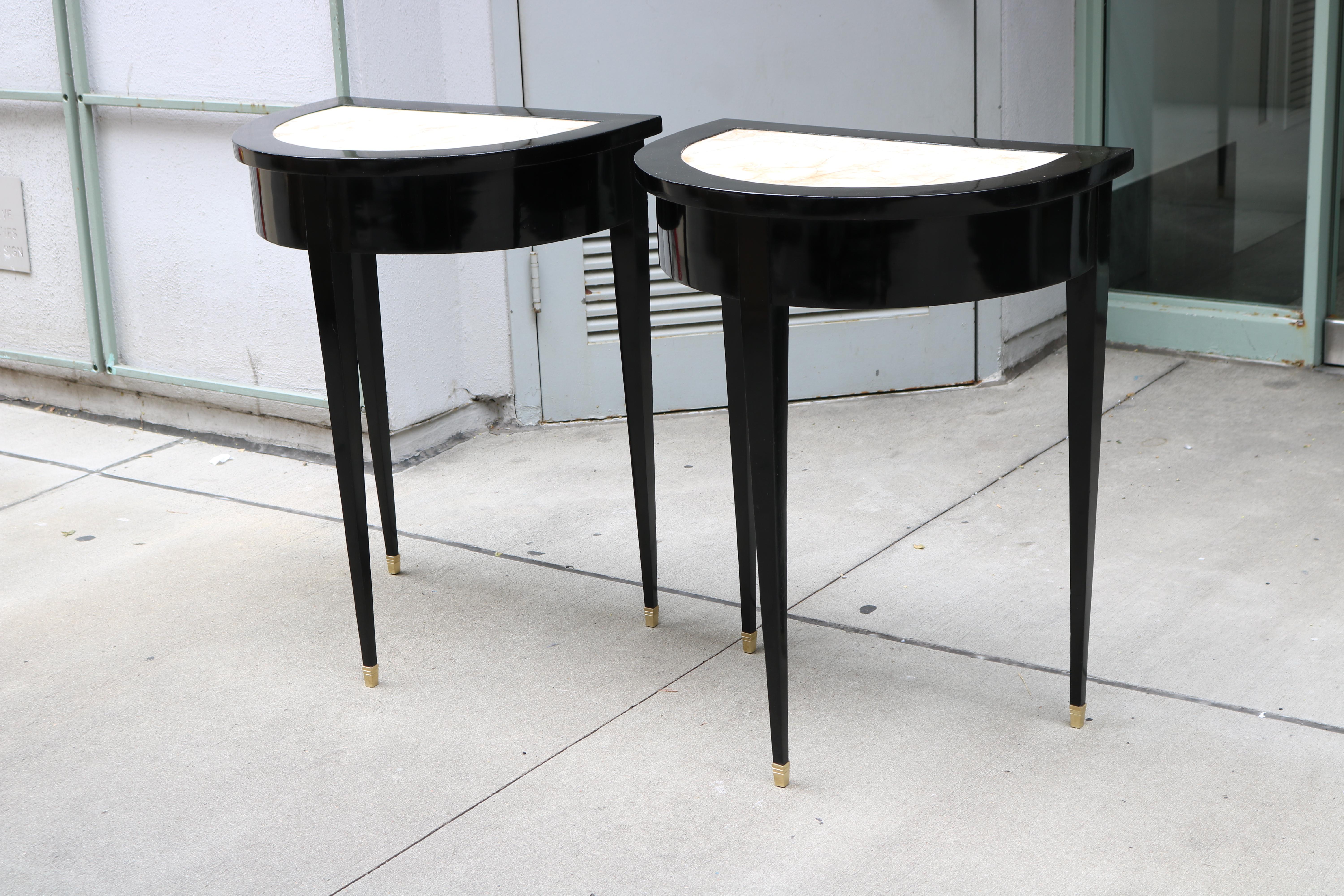 Pair of Ebonized Neoclassical Demi Lune Marble Top Consoles. 
Ebonized wood with marble tops and brass sabots.