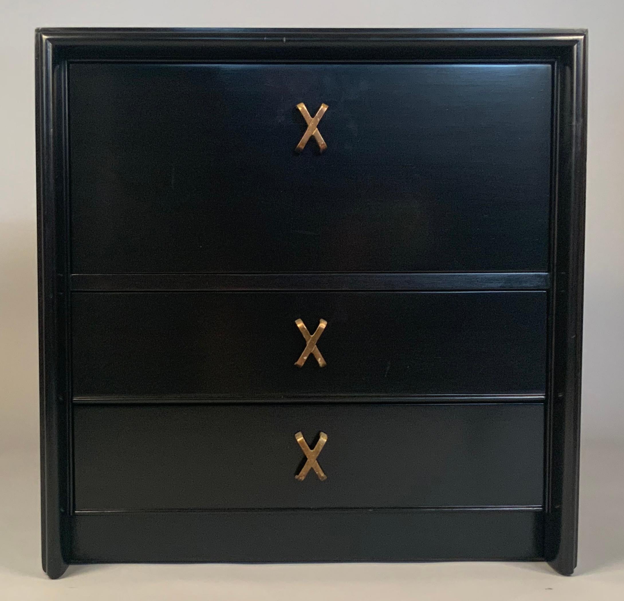 A very handsome classic pair of 1940's nightstands, with ebonized mahogany cases. Each has a pair of drawers underneath a large open storage space with a hinged drop-down door. the stands have their original brass X drawer hardware.