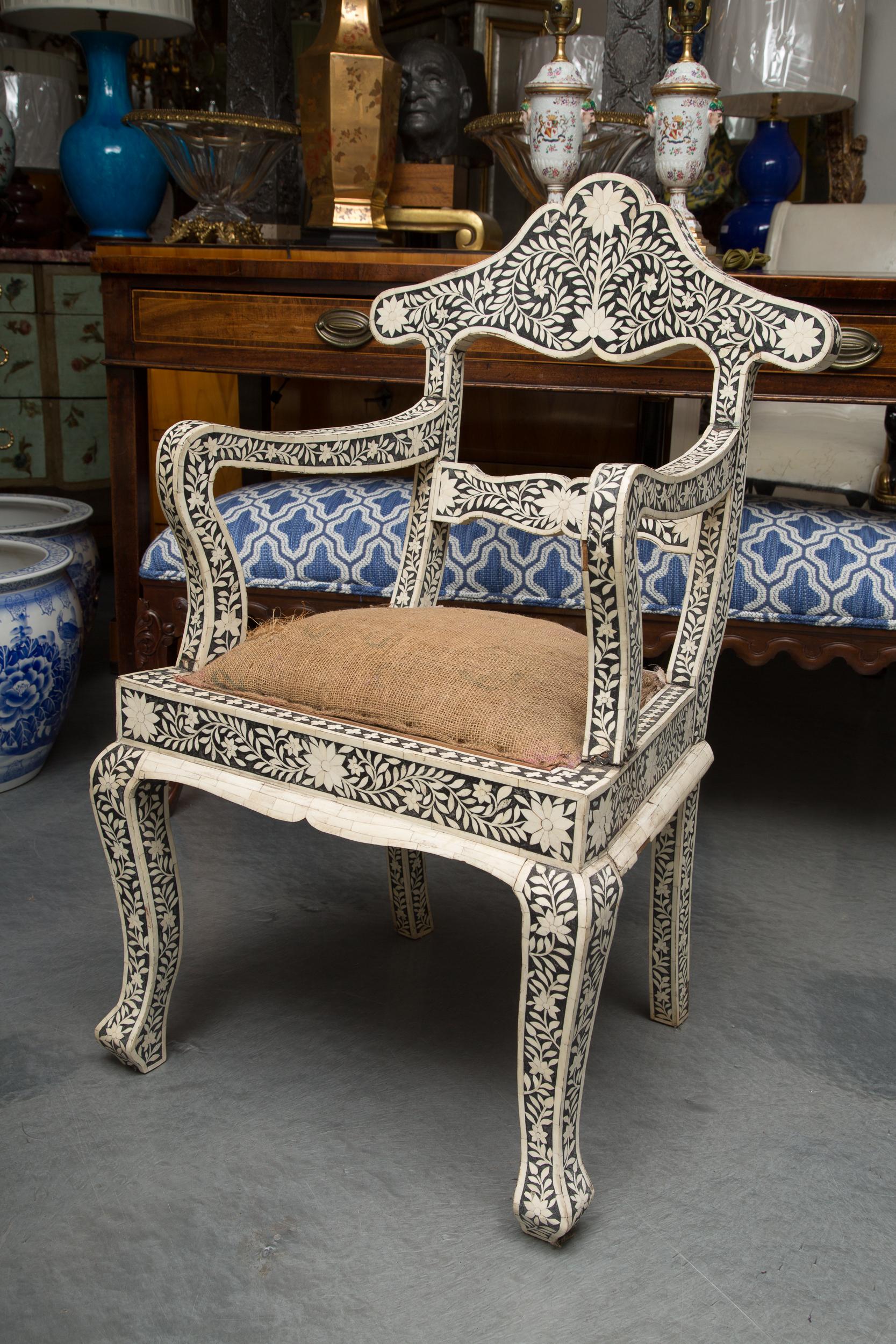 This is an exquisite pair of ebony Moroccan armchairs profusely inlaid with intricate bone. The overall design creates sprays of foliage and flower heads, circa 1920.