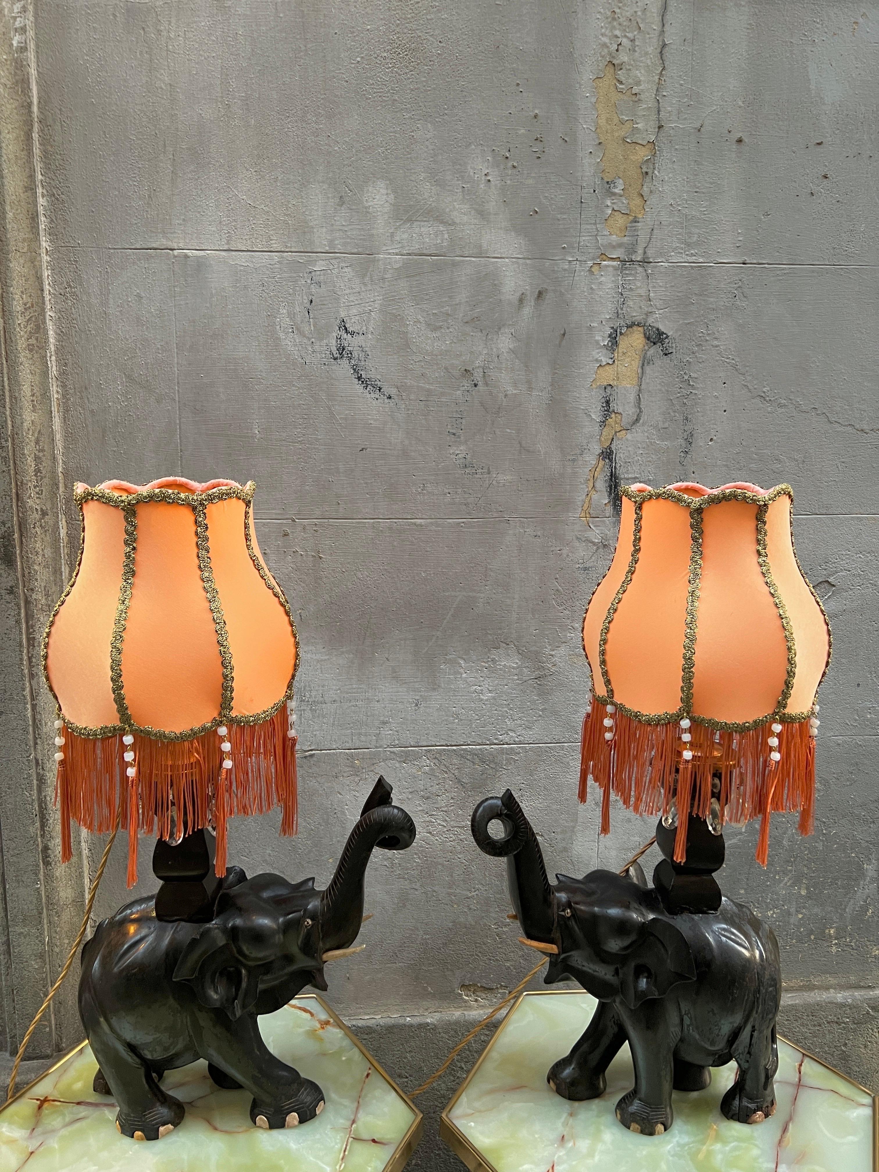 Pair of Ebony Elephants Table Lamps with our Handcrfted Orange Lampshades with fringes and bronze trimming borders.
The Black Ebony Wood Sculptures are inspired by the exotic colonial period of the Early 20th Century.
One light bulb each lamp.
