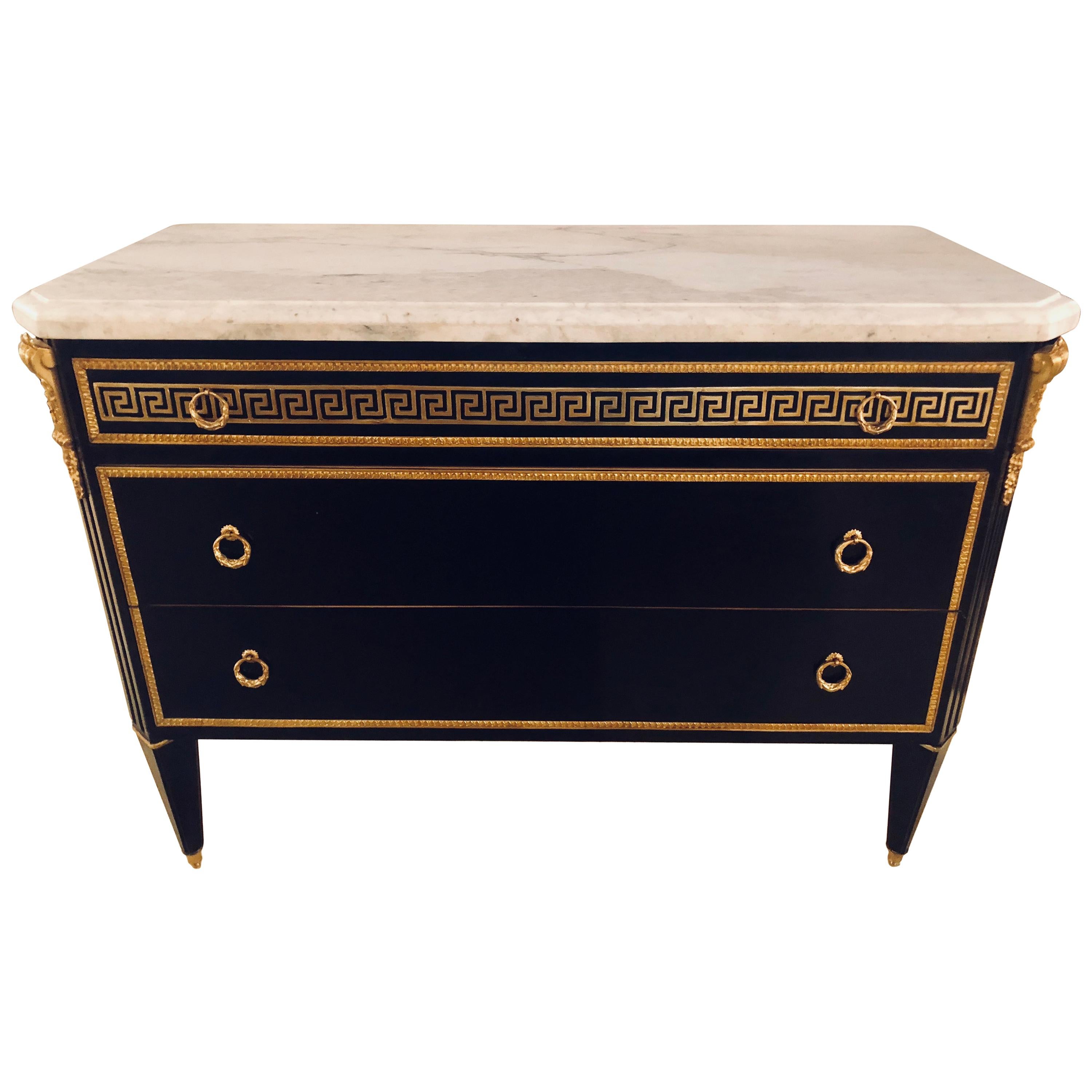 A pair of ebony Jansen style Greek key bronze-mounted marble-top commodes. Three-drawer commodes with Greek key bronze mounts and bronze drawer frames.
Simply the finest in quality and style come this pair of Hollywood Regency style ebony bronze