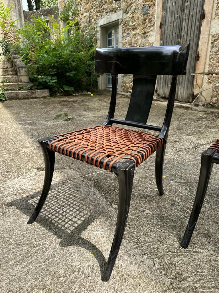 Behold this remarkable pair of Ebony Klismos Chairs, a captivating testament to mid-century modern design influenced by the visionary Robsjohn Gibbings. Crafted in Paris and the USA during the 20th century, these chairs exemplify timeless elegance