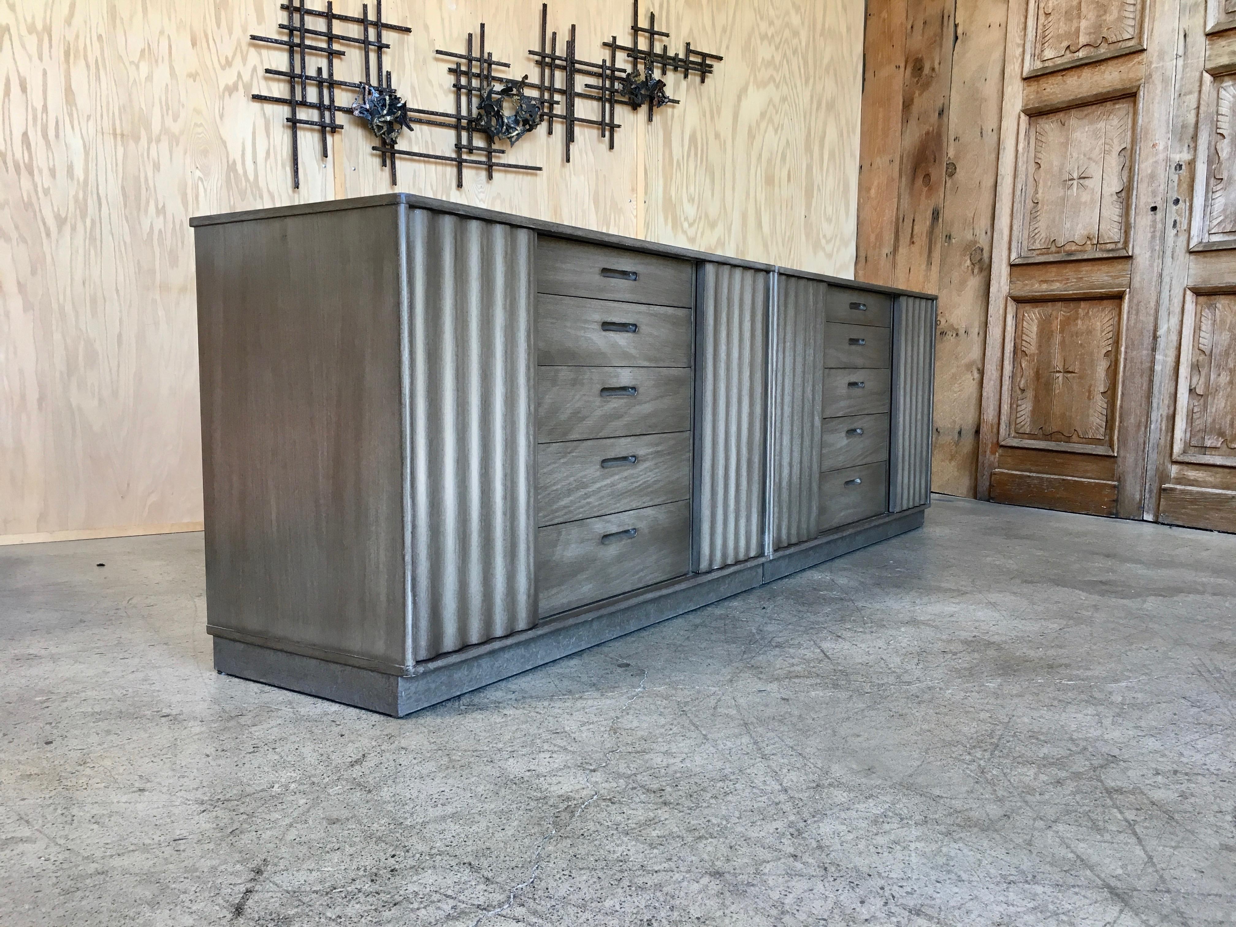 Two Edward Wormley cabinets with corrugated wood sliding doors and center drawer section in a grey brown finish
Each cabinet is 20
