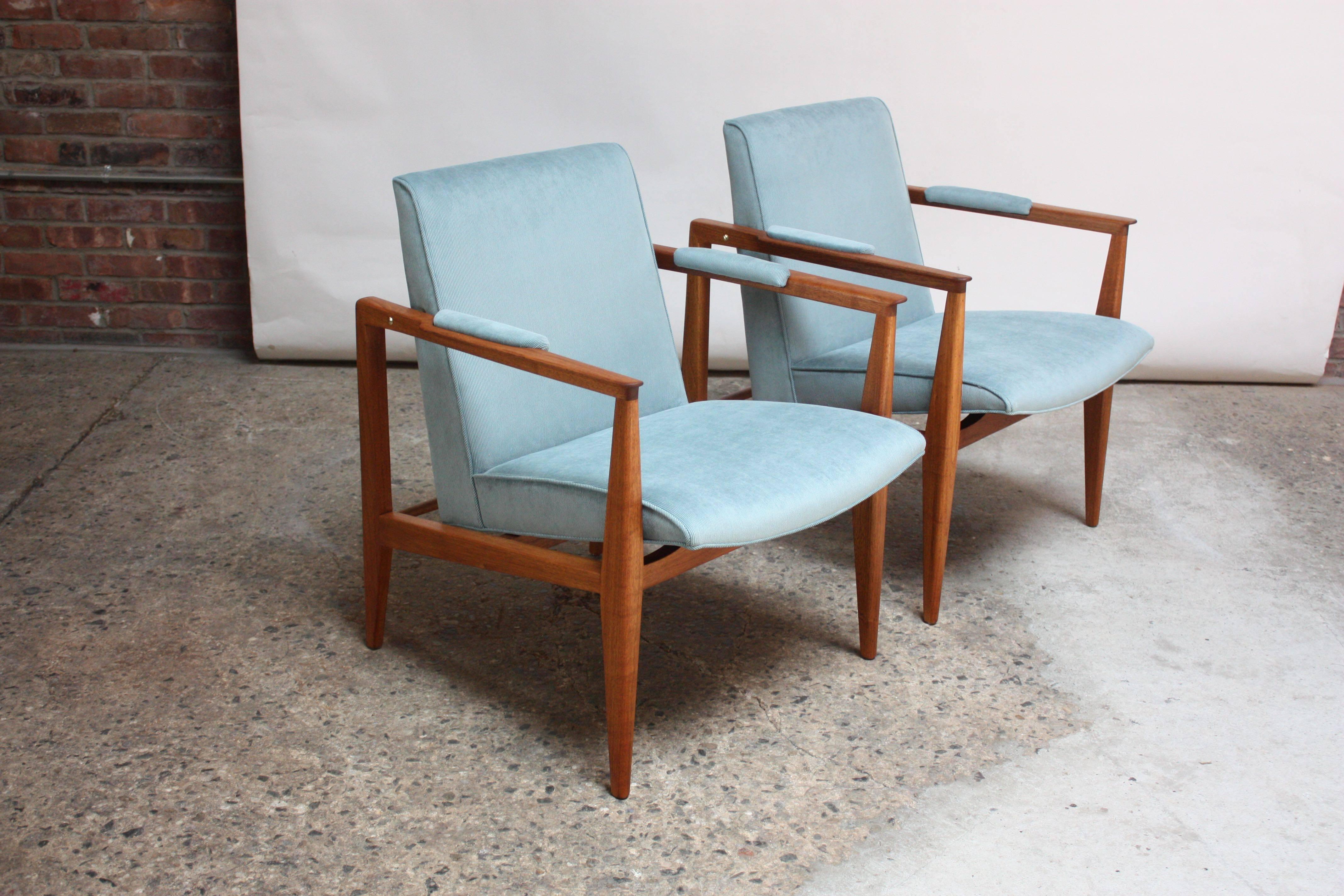 Exquisite and uncommon Dunbar armchairs composed of mahogany frames, brass accents and covered in a light blue corduroy (a tightly woven corduroy whose wales / ribs are close together - swatch available upon request). The color photographs slightly