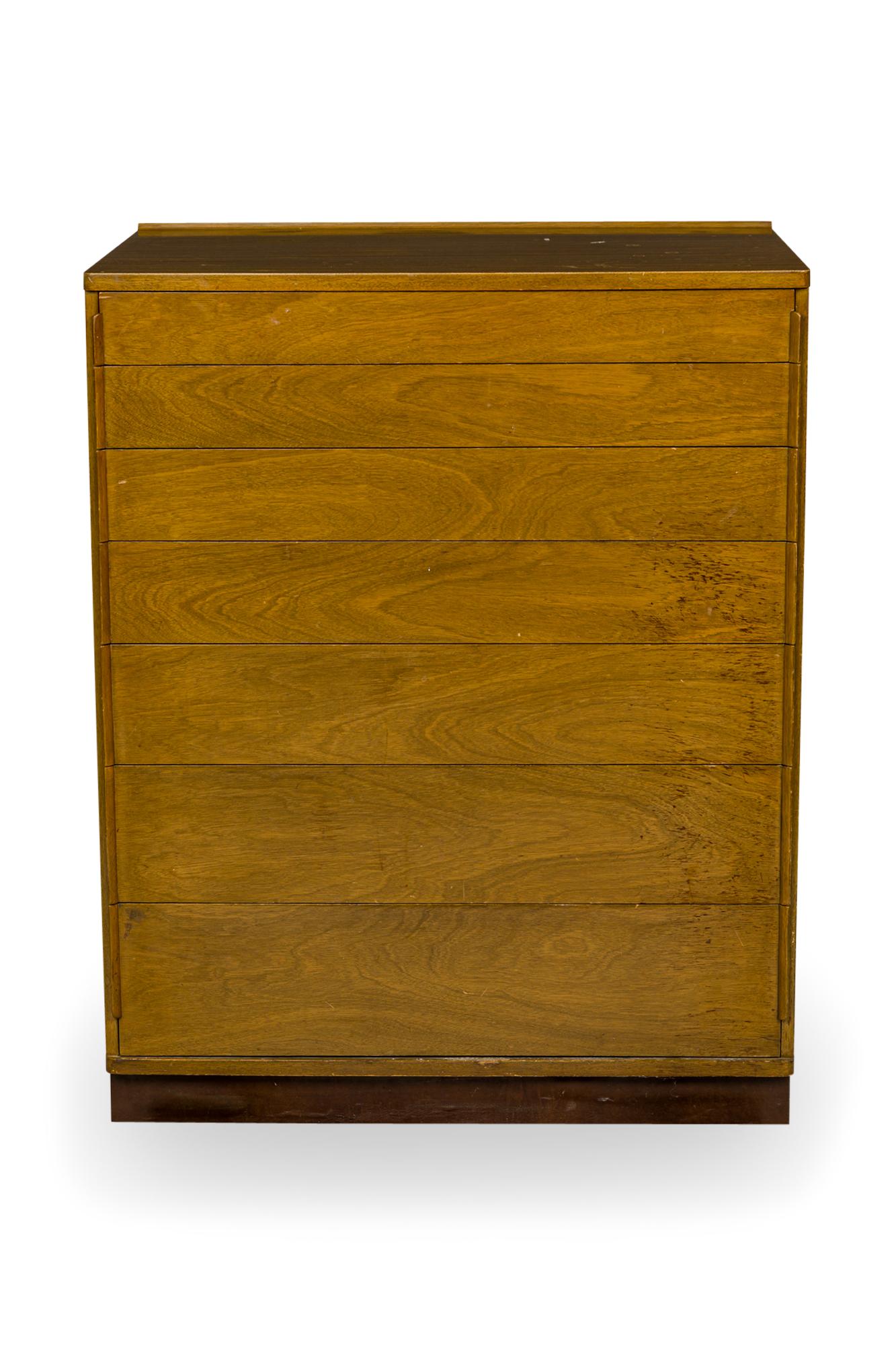 PAIR of American Mid-Century 7-drawer chests with walnut veneer, and drawers in graduating size with thin plywood drawer pulls on the sides of each drawer front, resting on a brown leather-wrapped plinth. (EDWARD WORMLEY FOR DUNBAR FURNITURE