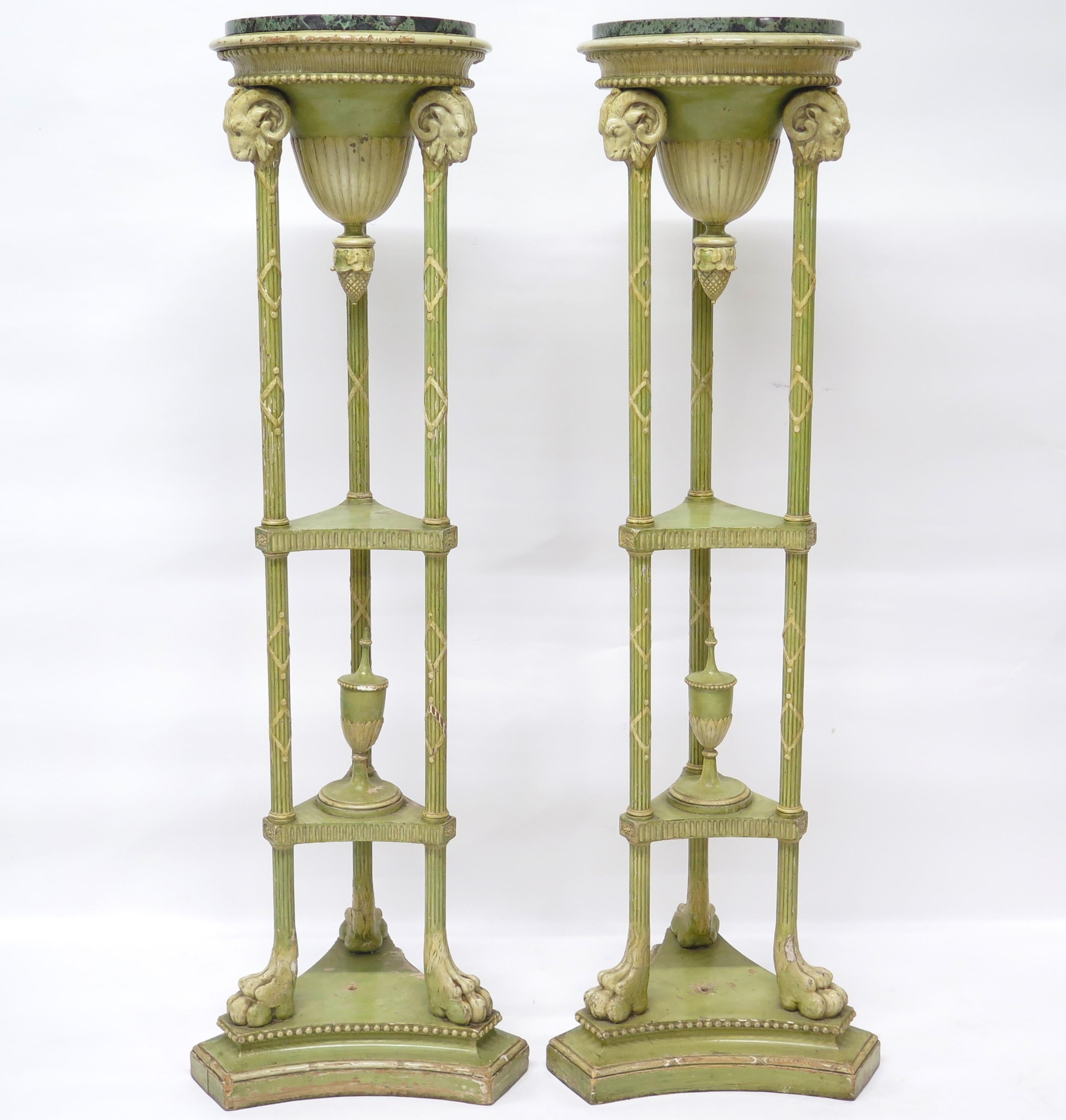 a handsome, tall, slender, elegant pair of Adam-style painted (greenish) candle stands (or plant stands) supported by three columns with lion's paw feet and ram's heads, green grey and black round marble tops. England, Edwardian, circa 1910