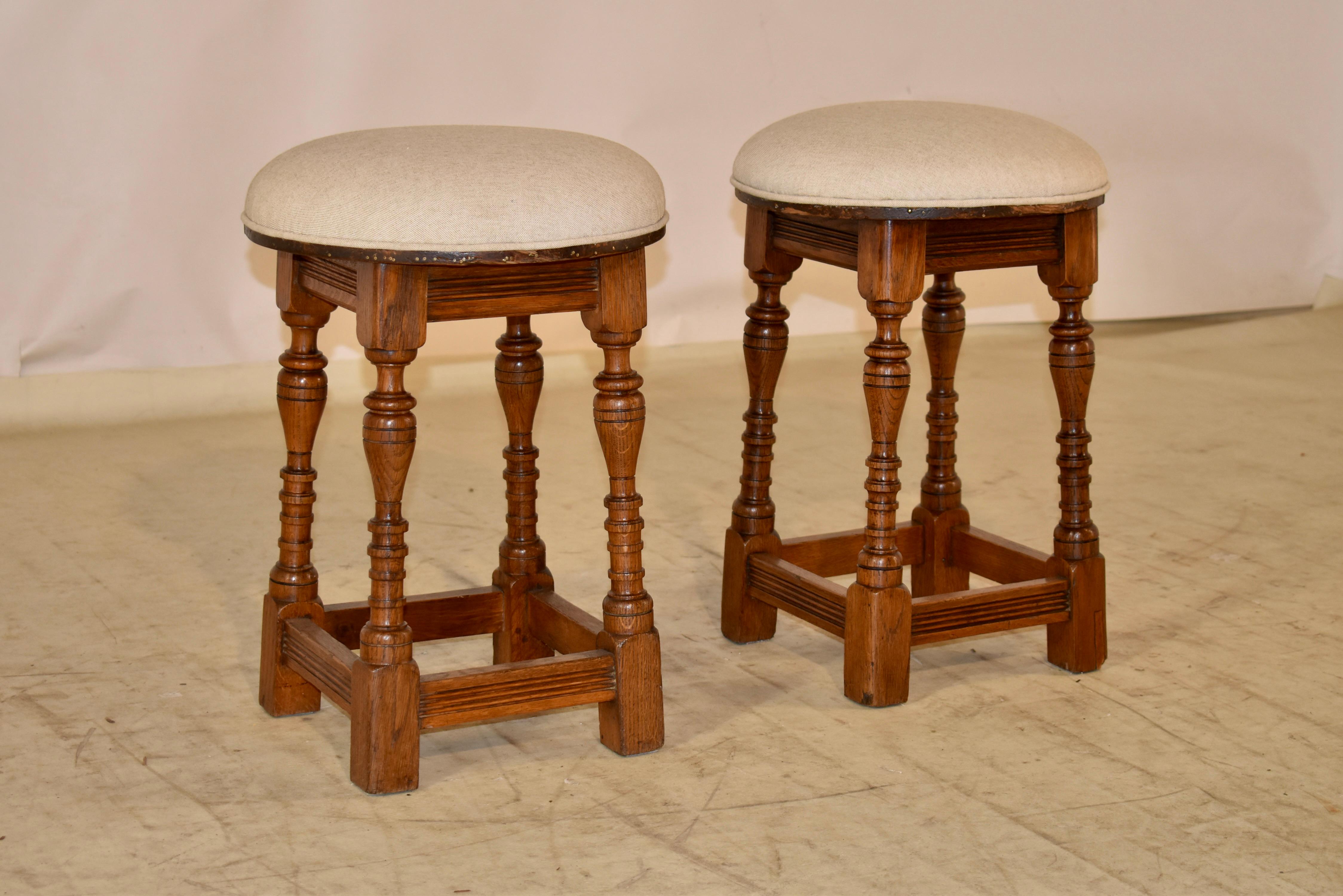 Pair of interesting Edwardian oak stools from England.  The seats have been newly upholstered in linen and finished with single welt decoration.  These are a great pair of quirky stools, which have simple aprons and lovely hand turned legs which are