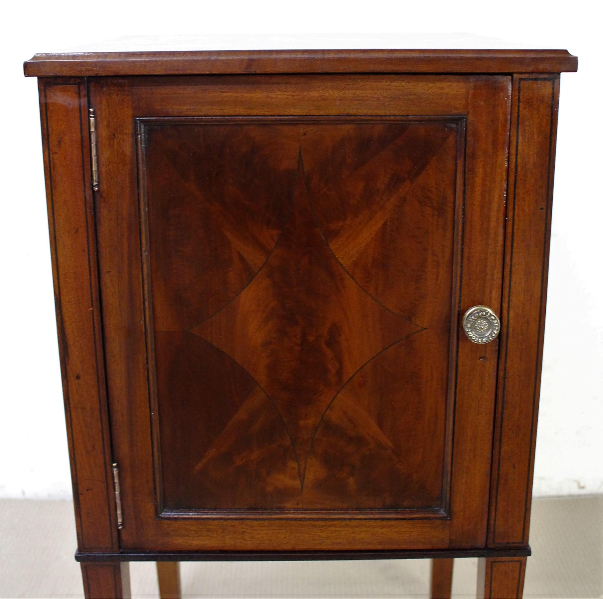 A lovely pair of Edwardian period inlaid mahogany bedside cupboards. Each with a single opening door, fitted with their original brass handles, which open to access shelved interiors. Decorated with inlaid stringing in ebony and with a decorative