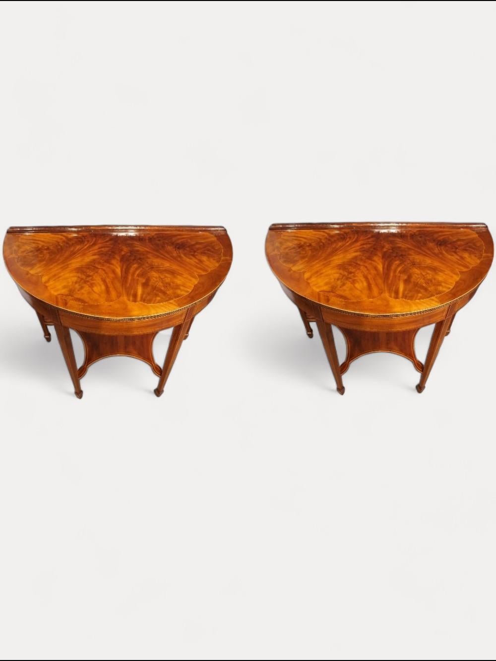 Paar edwardianische Demi-Lune-Tische
Dieses Paar edwardianischer Demi-Lune-Tische stammt aus der Zeit um 1910.
Jeder Tisch hat quadratische, spitz zulaufende Beine, die mit Spatenfüßen enden.
Die halbrunden Platten mit den geformten Intarsienmustern