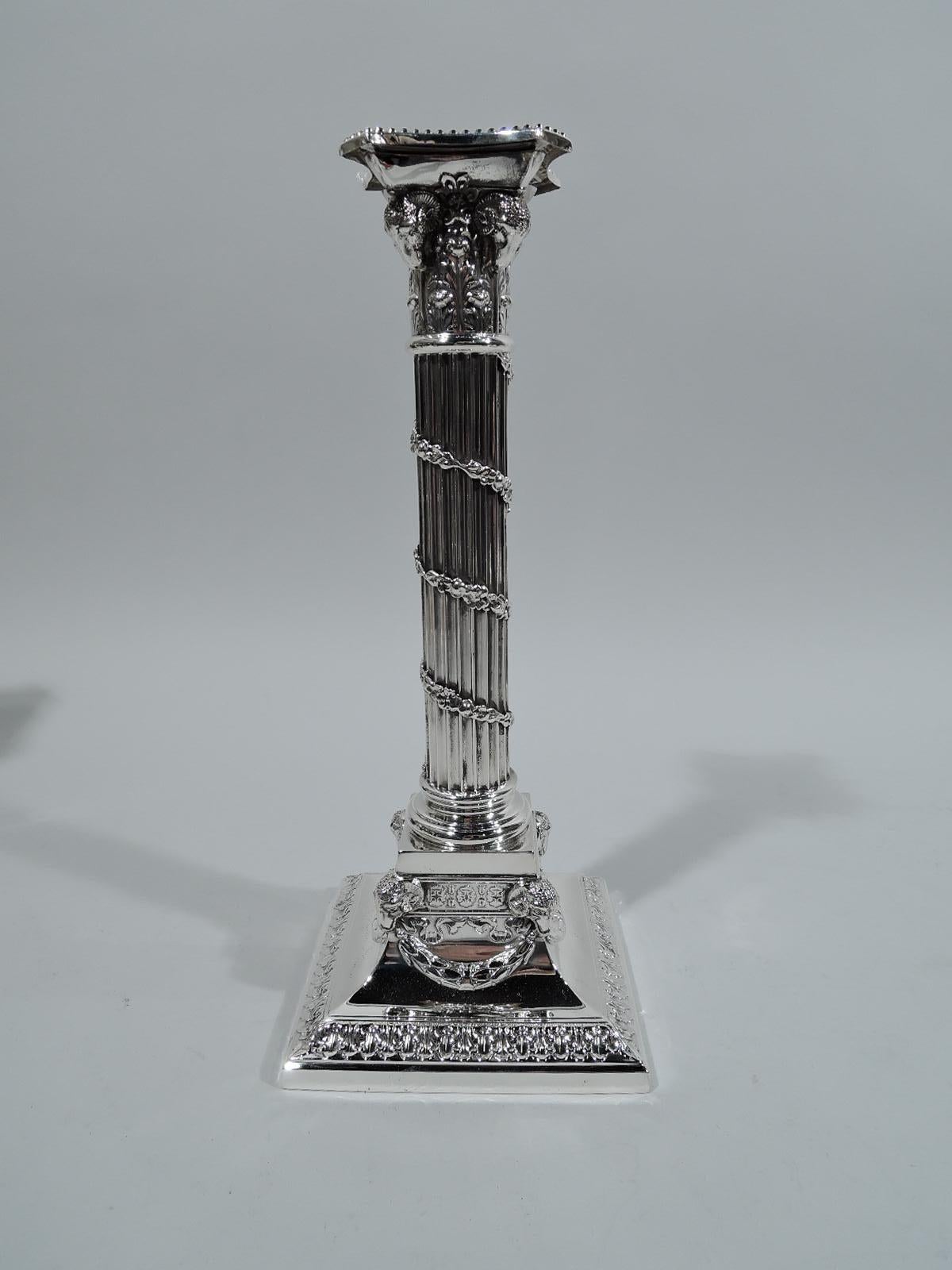 Pair of Edwardian neoclassical sterling silver candlesticks. Made by Mauser in New York, circa 1910. Each: Fluted column with descending wraparound garland. Composite Corinthian capital with ram’s heads. More ram’s heads applied to square base