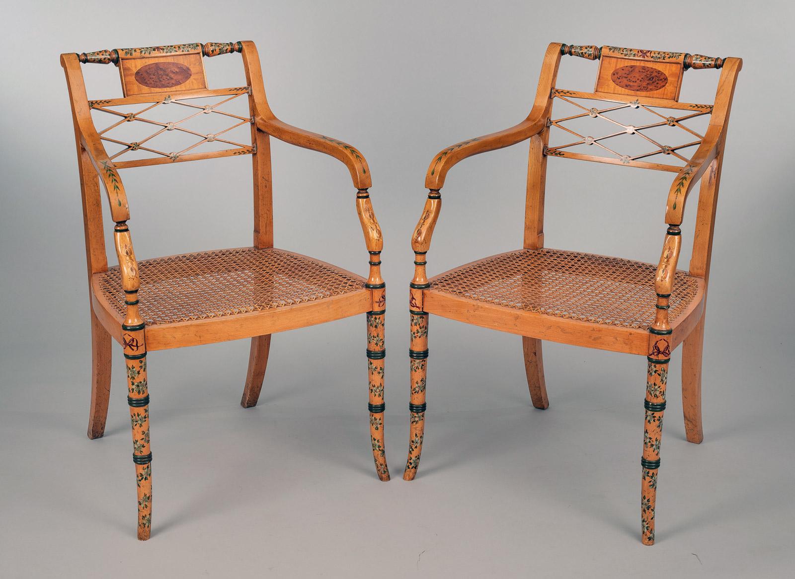 Pair of Edwardian satinwood and painted armchairs with a turned top rail above a rectangular panel enclosing a burr elm veneer oval, above an open latticework splat, scroll arms extending to carved supports, caned seats, supported on ring turned
