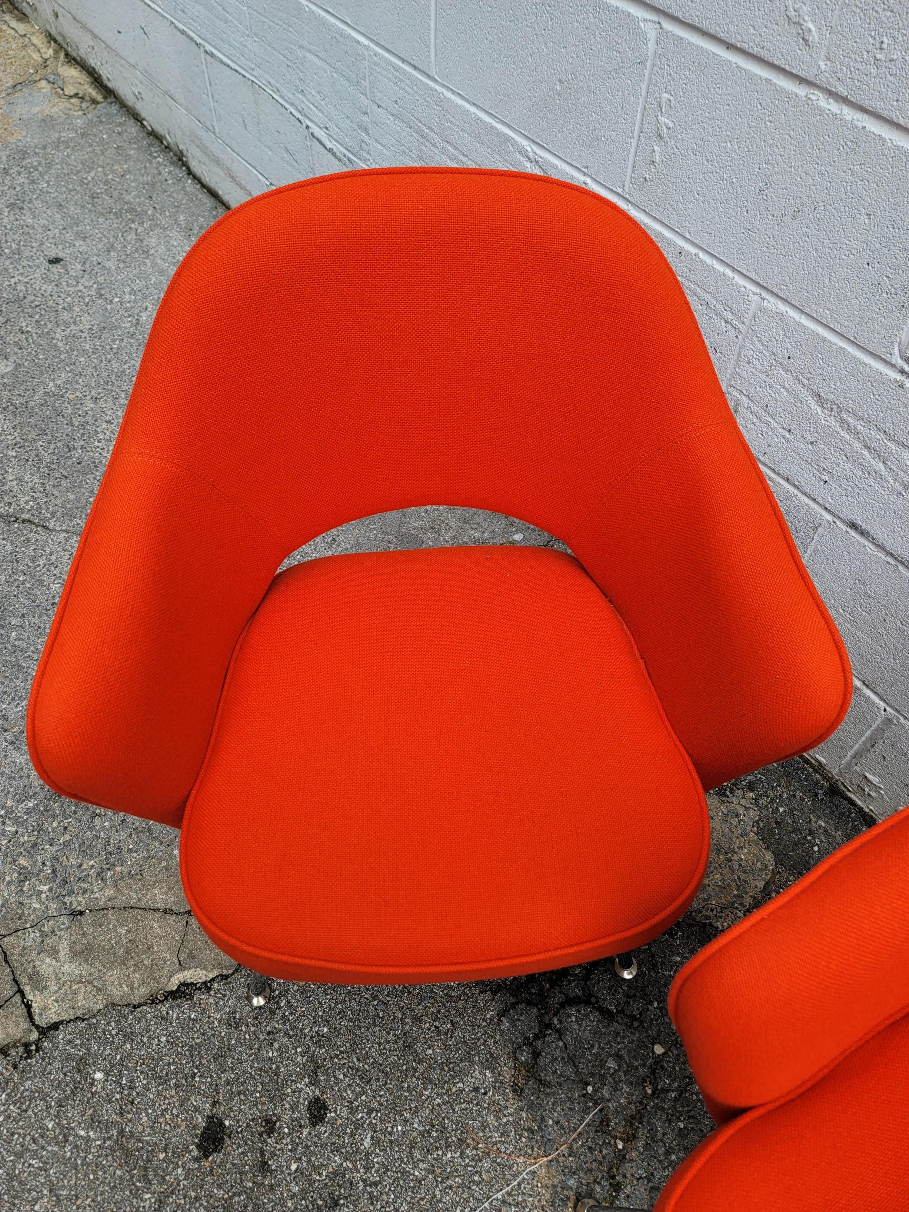 Pair of executive arm chairs designed by Eero Saarinen for Knoll. The orange fabric is in very good condition with nice foam and clean, shiny chrome legs. Labeled Knoll.