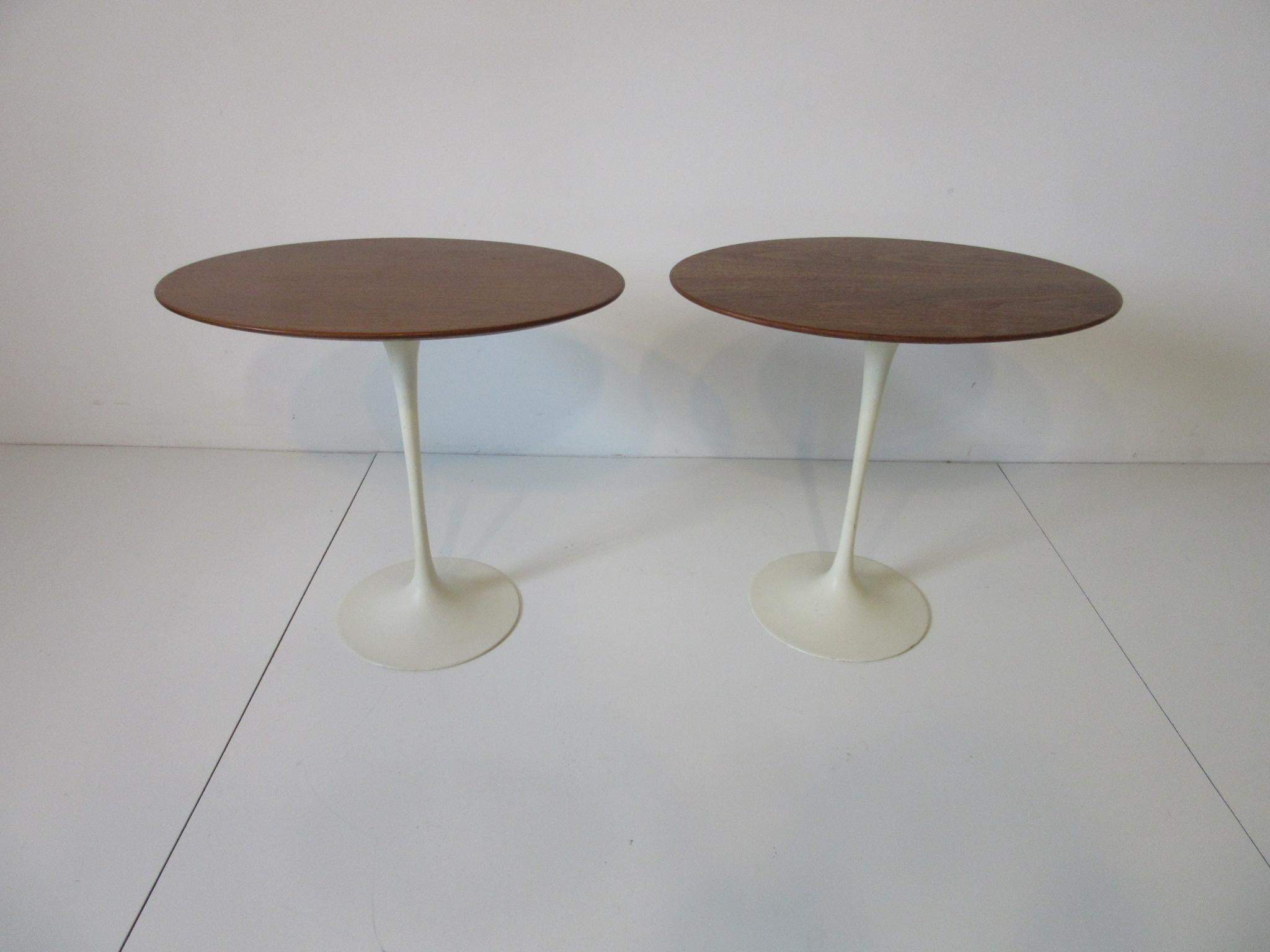 A matching pair of Eero Saarinen designed side tables with oval walnut tops and creamy white cast bases. Retains the manufactures label Knoll -Park Ave, NY. NY and ink date stamped 1972. A pair that are matched from birth are hard to find since they