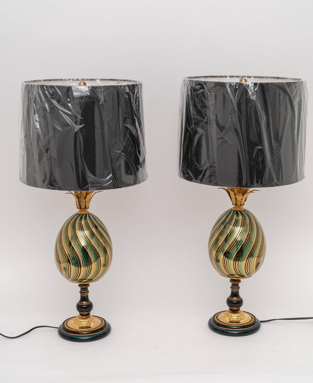 This stylish set of table lamps are attributed to Maison Jansen and are fabricated in porcelain with and enameled colors in gilt gold, black and green, which complement the gilt brass palmetto fronds and mountings.

Note: Custom black paper shade