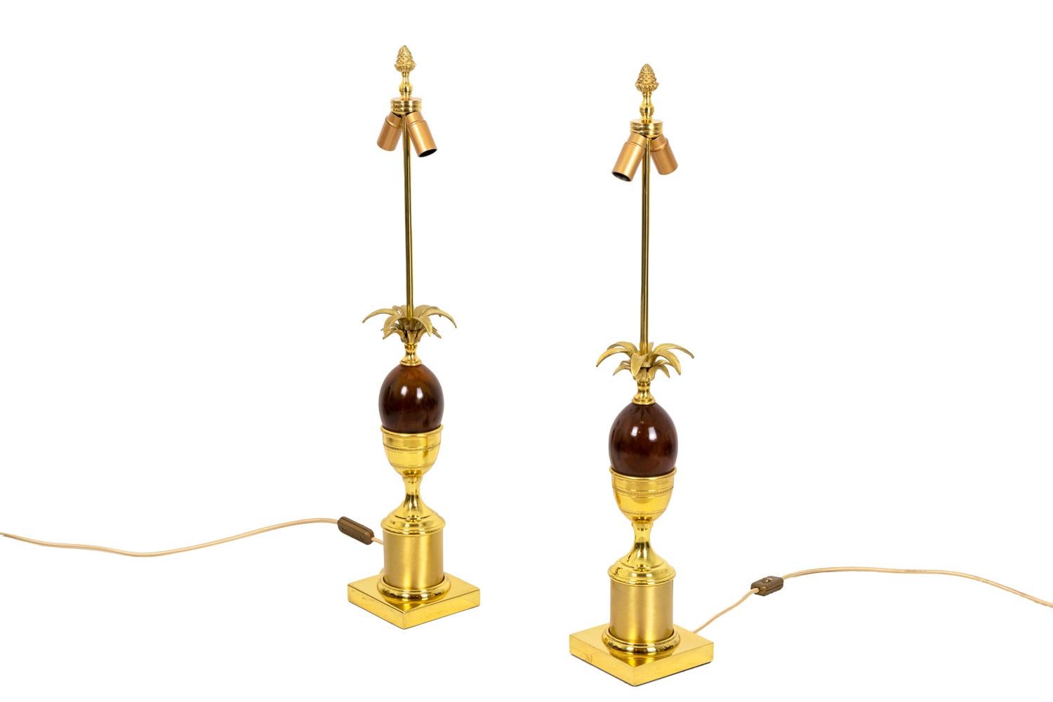 Pair of egg lamps in brown bakelite and gilt bronze. Lamp topped by a pine cone. Shaft in egg shape topped by palm tree leaves and standing on a cup adorned with water leaves friezes. Cylindrical base in brushed gilt bronze standing on a square