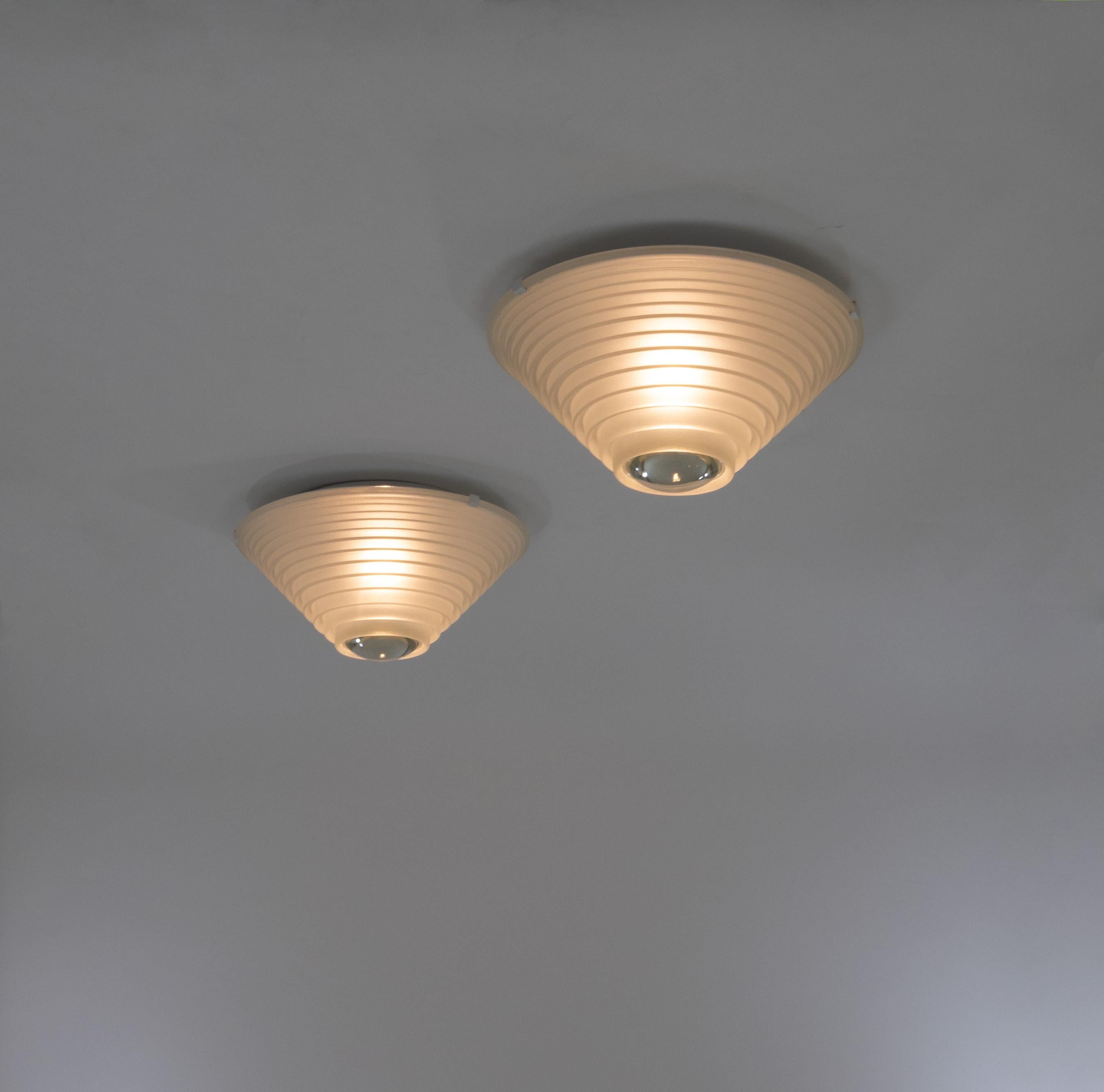 Coppia di lampade da soffitto o parete Egina 38 a luce diffusa e concentrata disegnate da Angelo Mangiarotti per Artemide nel 1979.

Realizzato con un paralume in vetro sabbiato con una grande lente al centro e una struttura in metallo laccato