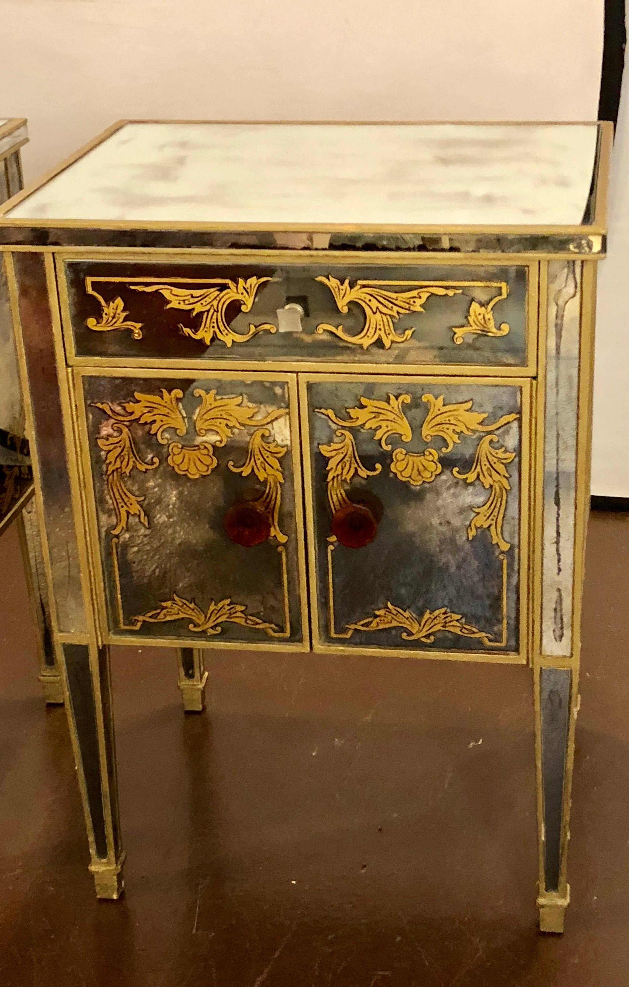 Pair of églomisé Italian mirrored nightstands or end tables. A pair of wooden vintage case with later decorated mirrored and églomisé decorated panels. The tapering legs supporting a pair of doors under a single drawer each distress decorated.