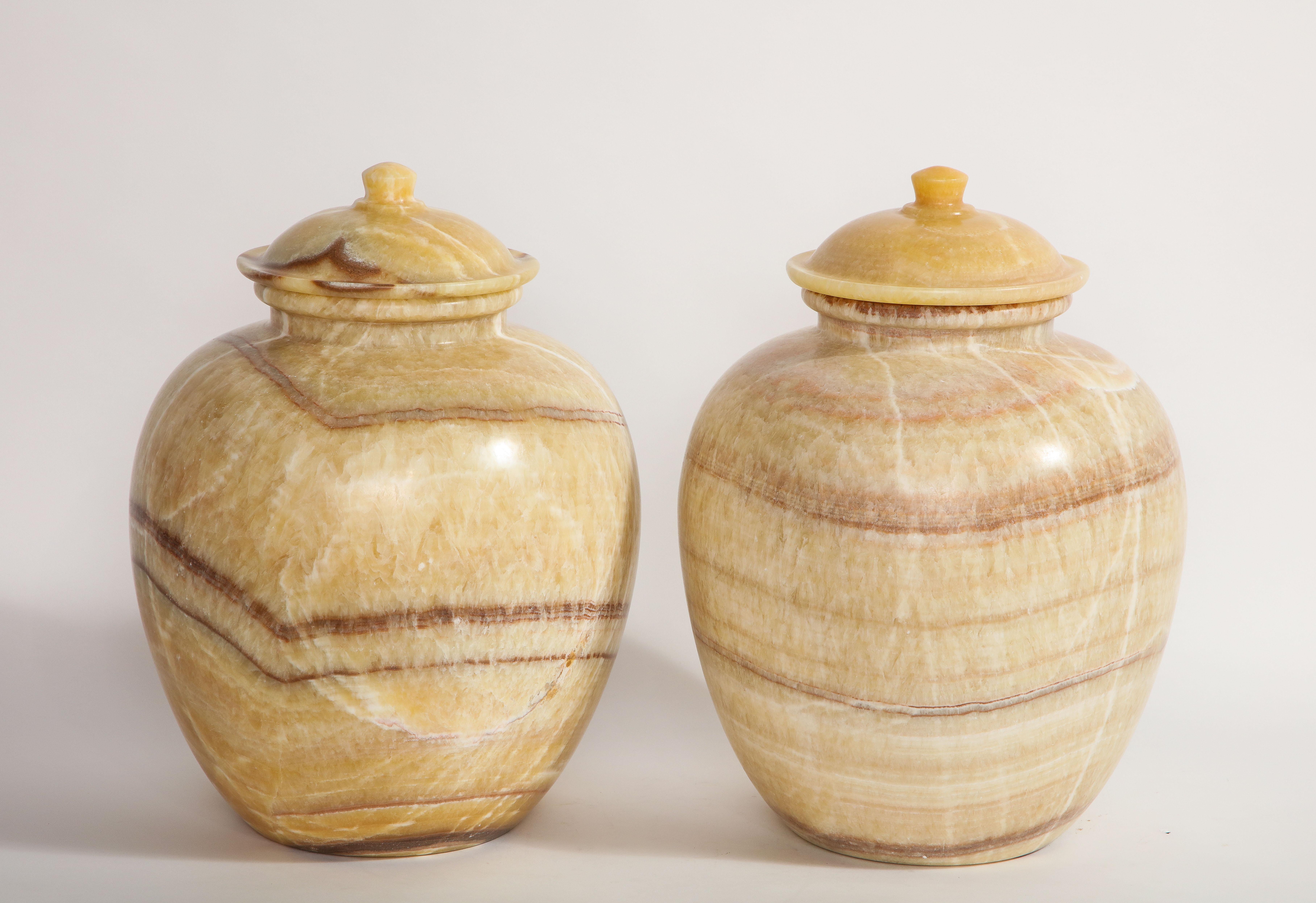 A beautiful and quite decorative pair of midcentury/Art Deco style Egyptian honey alabaster marble covered vases. Each is beautifully hand carved with gorgeous white, honey-yellow, and deep purple juxtaposing striations. These look fantastic in any