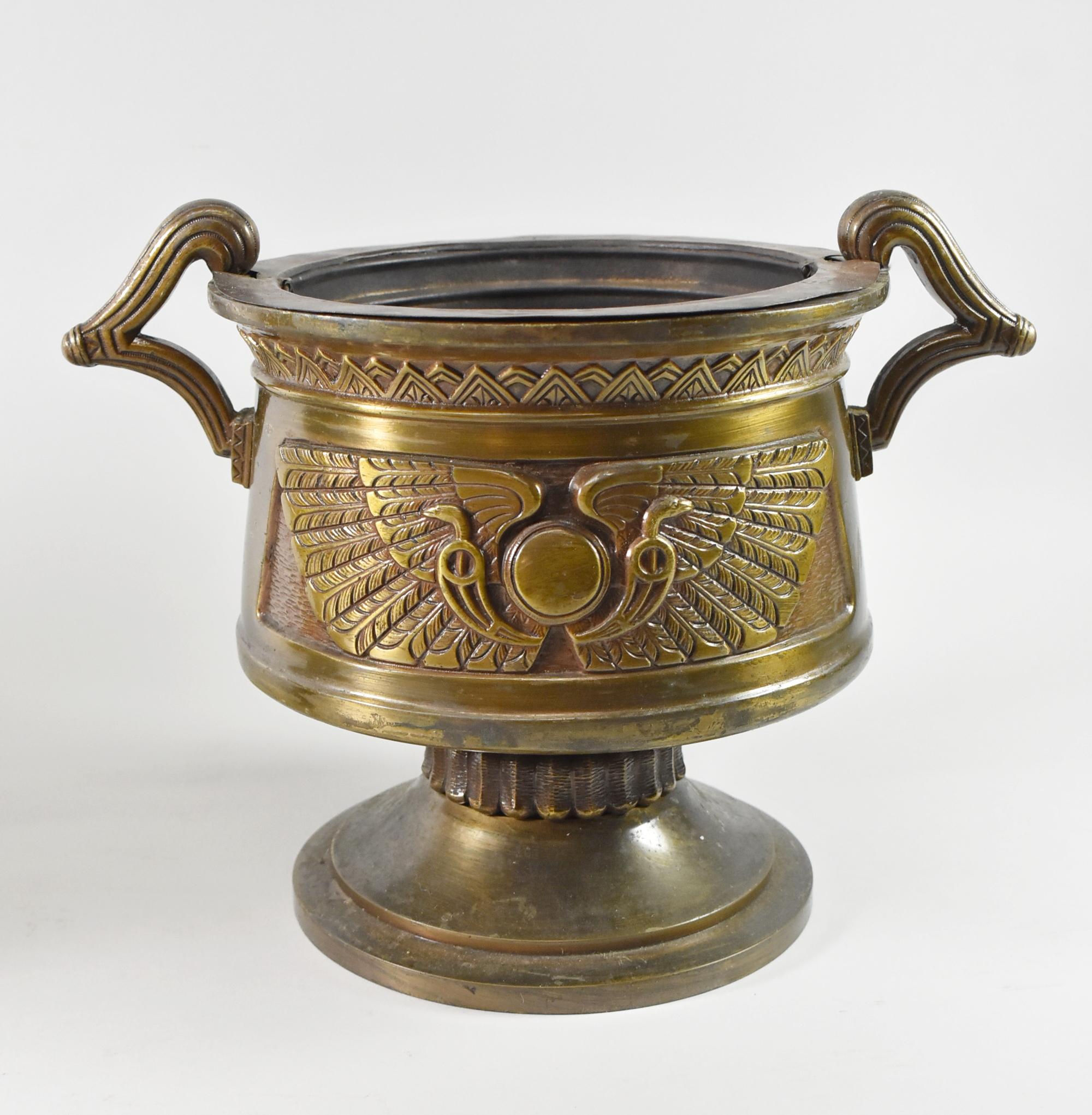 Paire d'urnes ou de jardinières égyptiennes en bronze en forme de soleil ailé, datant des années 1920. Belle patine avec des inserts en étain amovibles et des poignées doubles. Le recto et le verso sont ornés de symboles solaires ailés égyptiens. Le