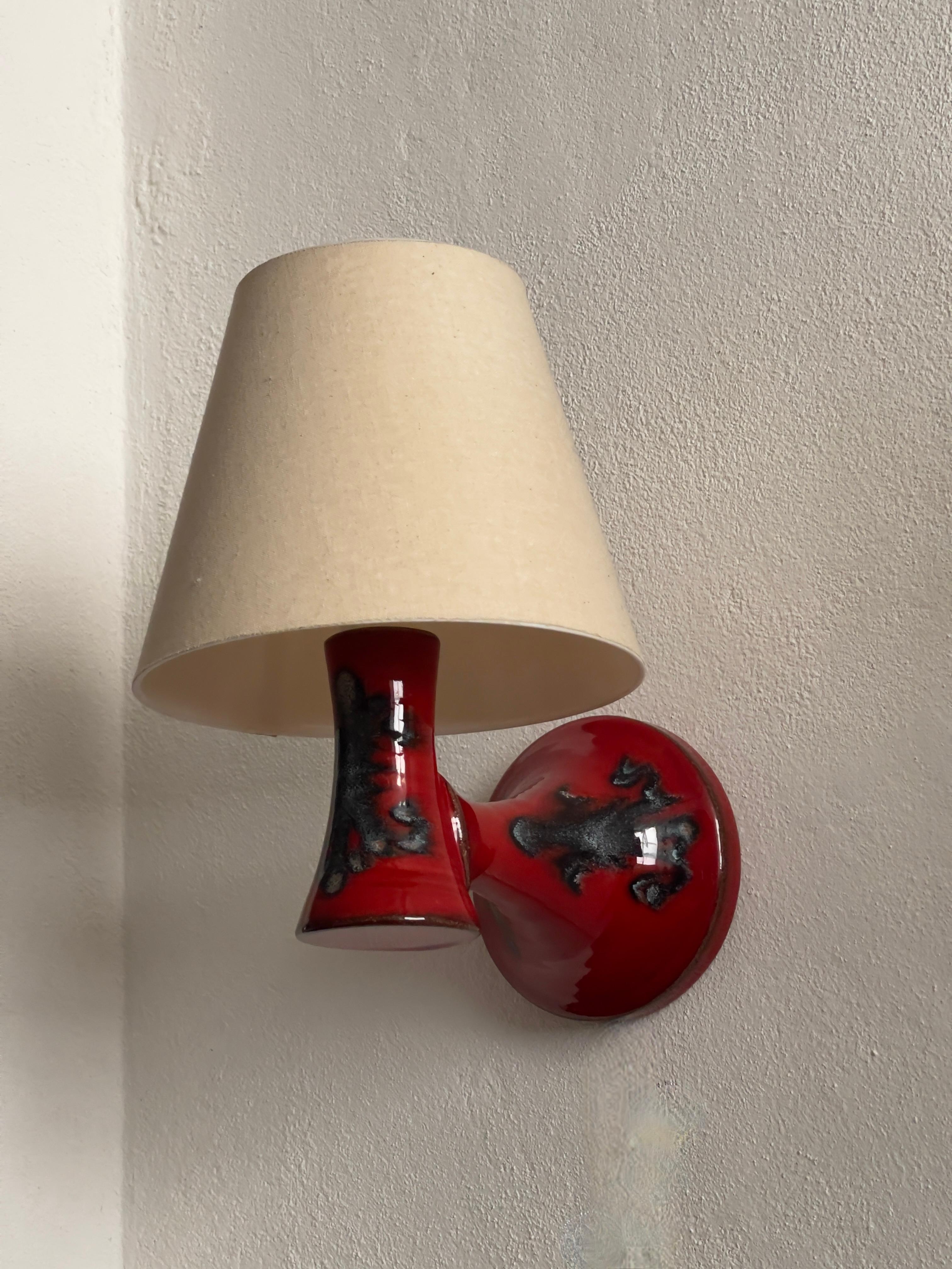 Rare pair of Danish modern ceramic wall lights with rich red and green glaze featuring an arrangement of abstract shapes.
Created by Lyskær in Denmark, 1960s. 
Including new linen shades and white cord.
In excellent condition.
Comes hardwired or