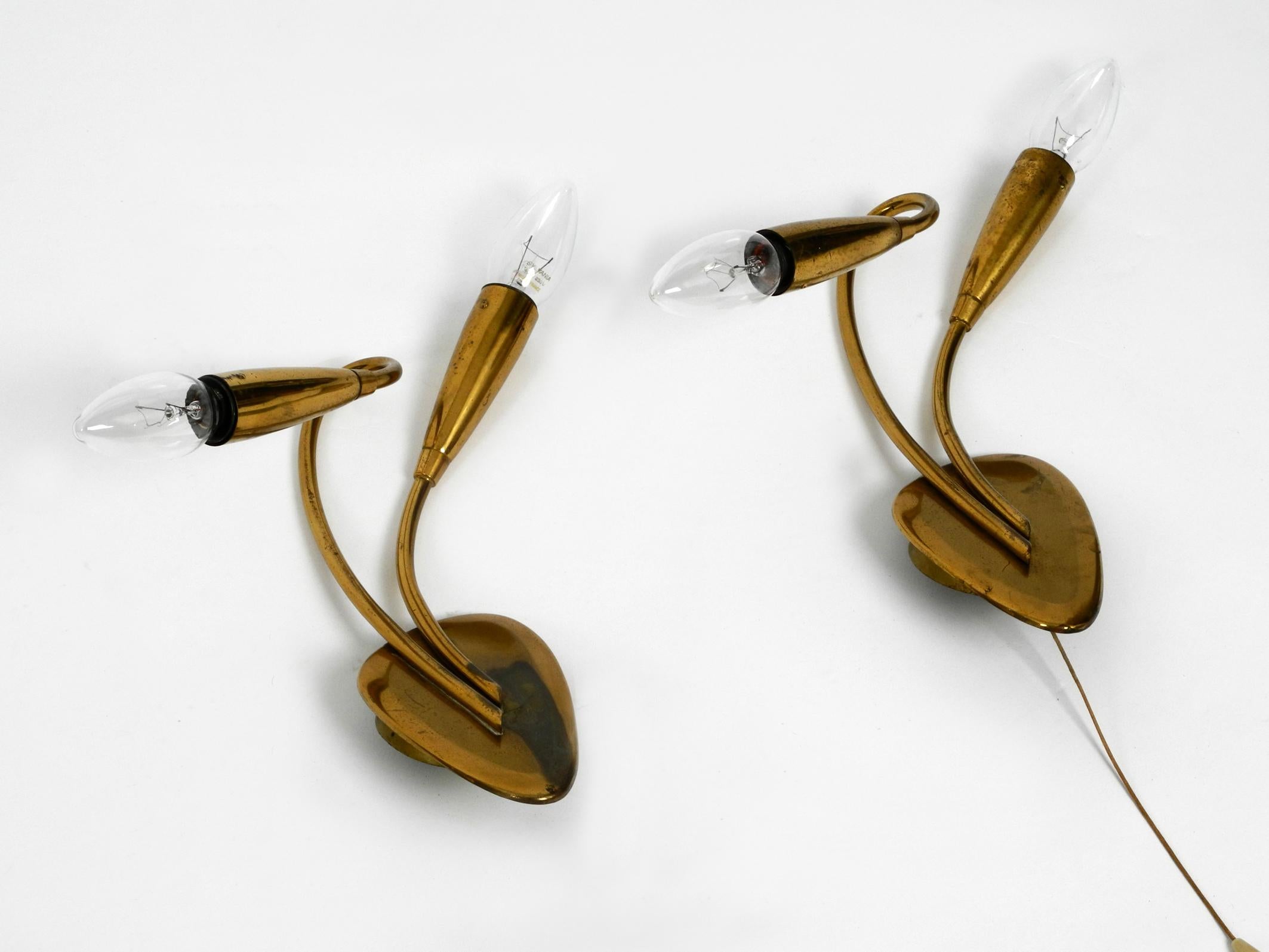 Pair of elegant 2-arm midcentury brass sconces.
Typical 1950s minimalistic design. Two E14 sockets each.
100% original condition and fully functional. Tested by an electrician.
Both lamps have a pull switch, but one cord is missing.
Very nice