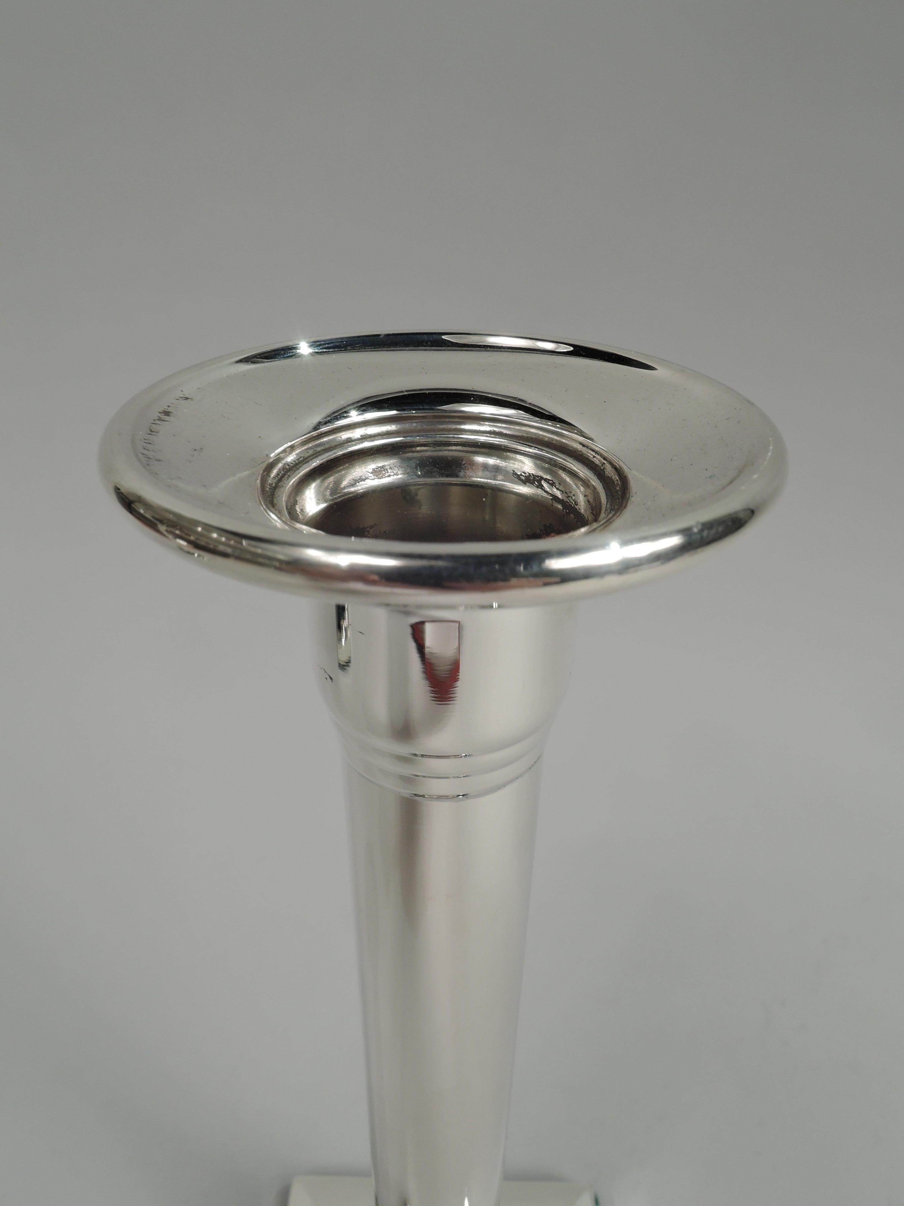 Pair of elegant American Modern Classical sterling silver candlesticks, ca 1920. Each: Columnar shaft with stepped top and bottom on raised square base. Felt-lined underside. Marked “Sterling / Weighted / 925”.